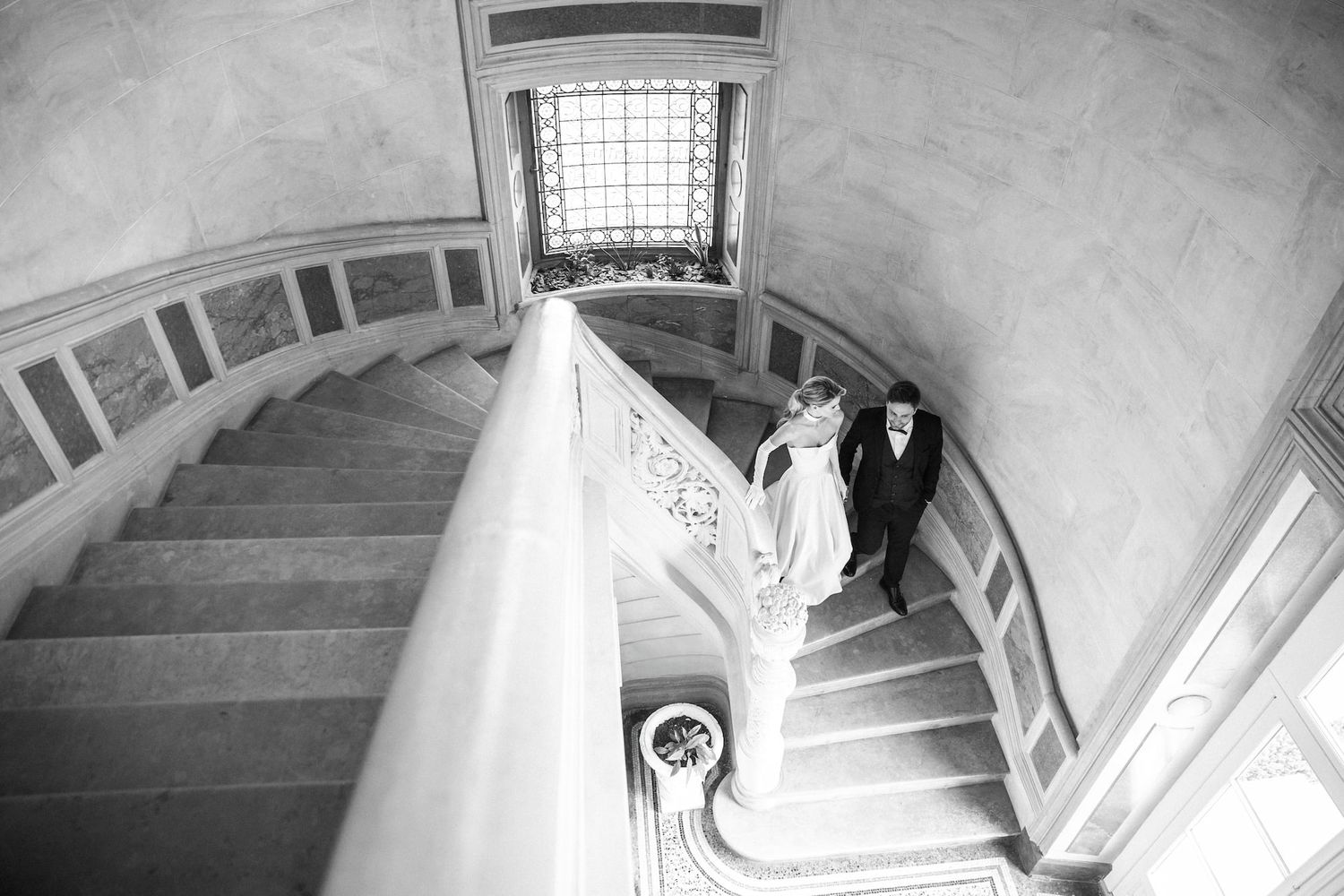 A candid moment of a couple walking down the staircase in a sophisticated French chateau.