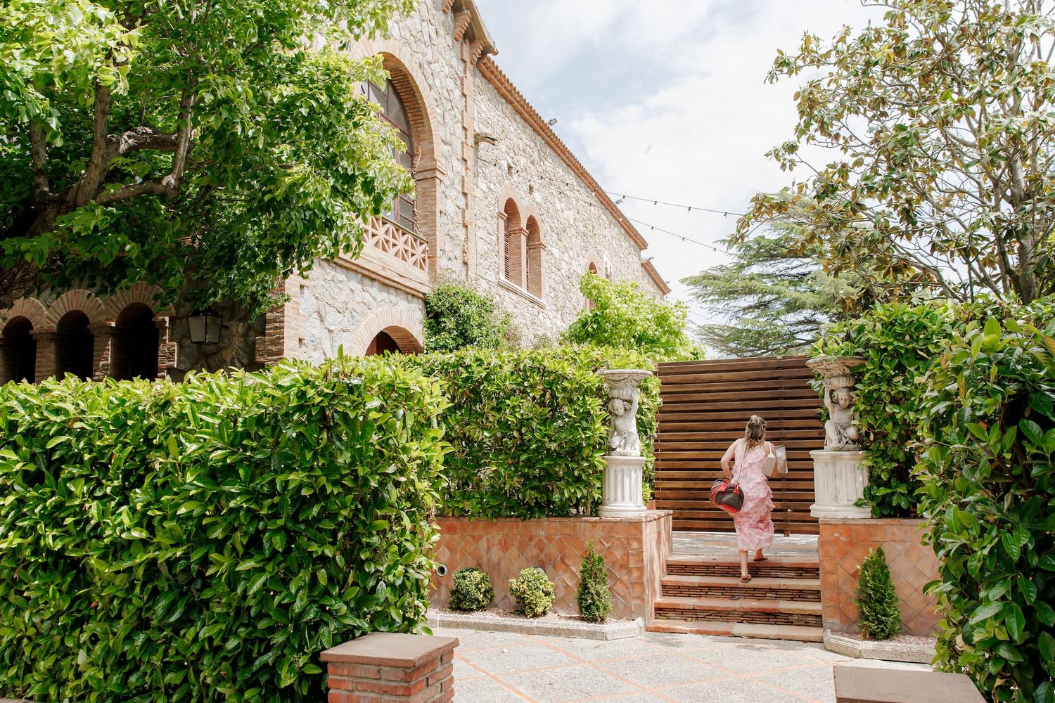Woman in a pink dress walking up stone steps of Mas de Sant Lleí