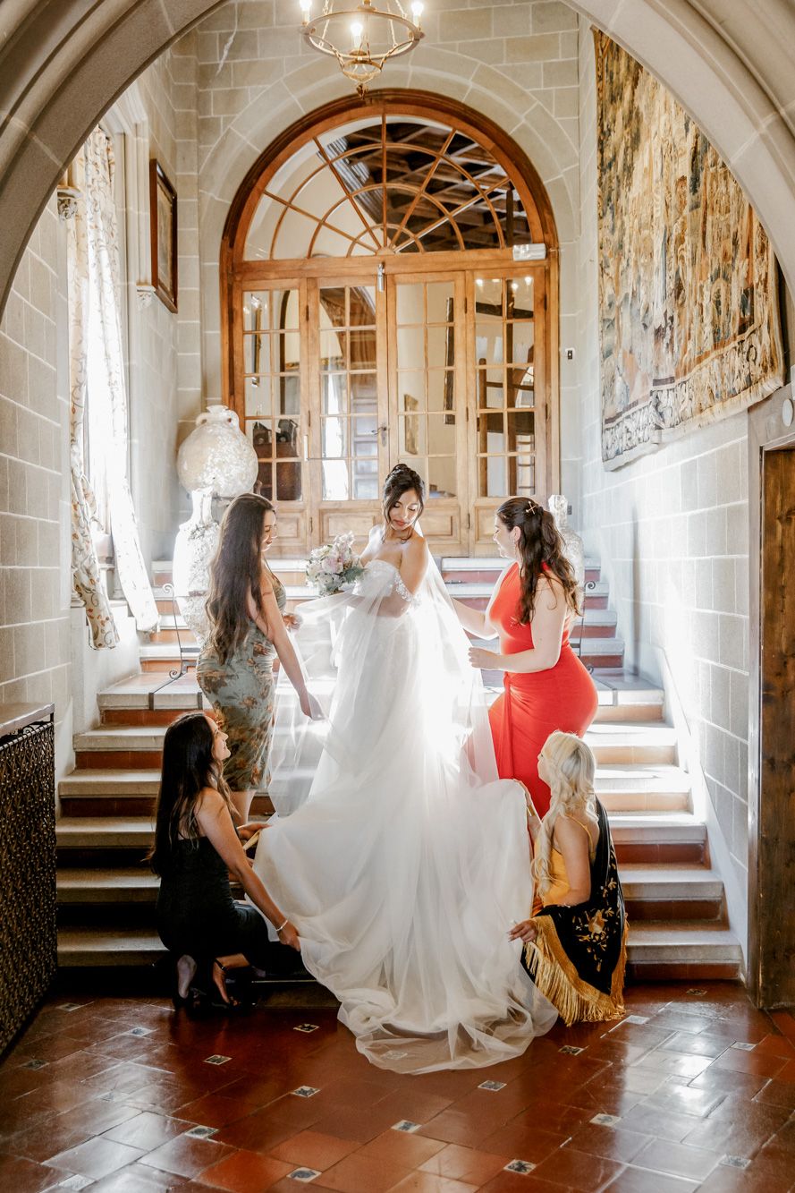 Bride in white gown surrounded by bridesmaids in elegant hallway at La Baronia | Wedding Photographer Barcelona | Spain Wedding Venue