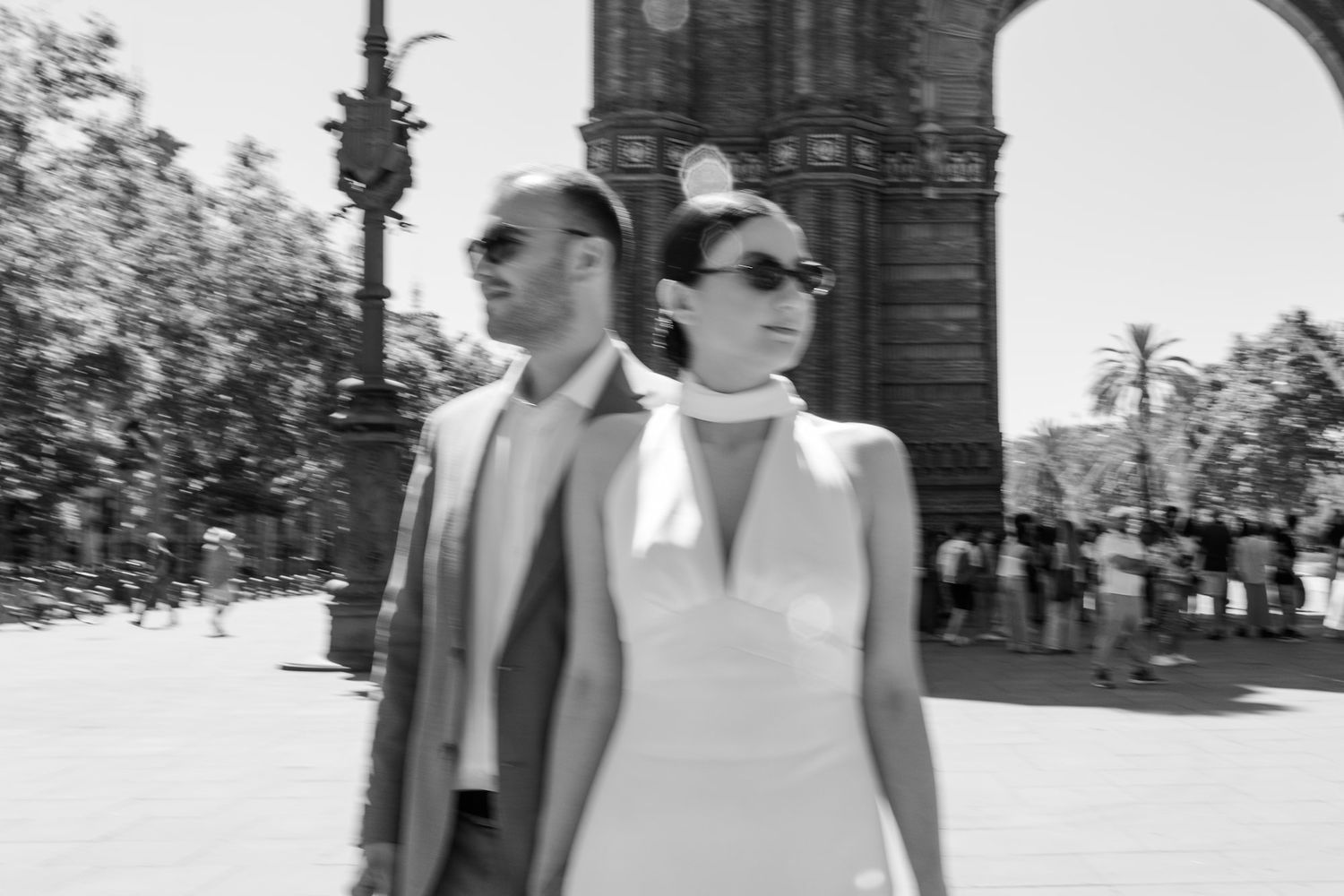 A black and white photograph showing people walking and conversing in a formal outdoor setting.