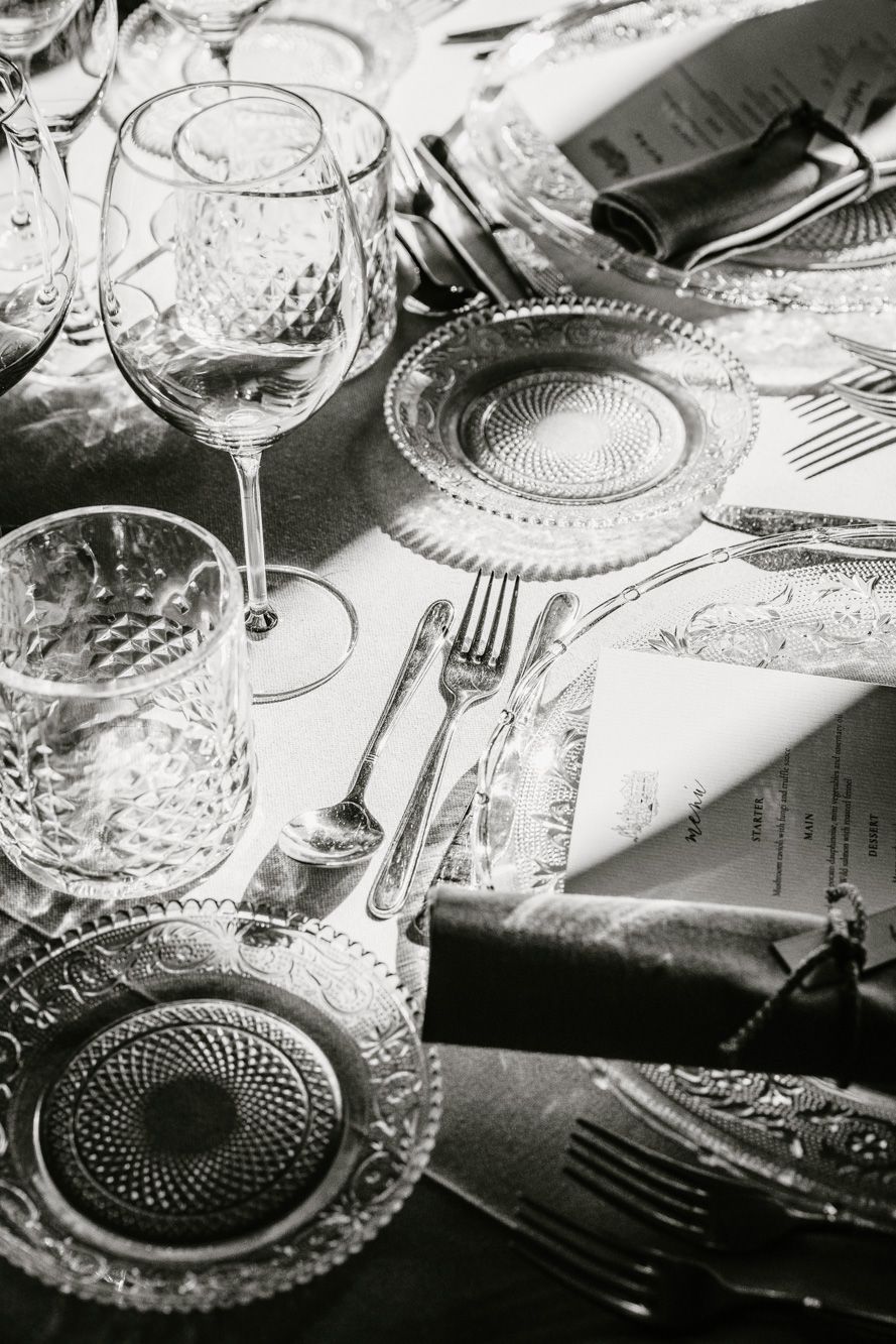 Elegant black and white table setting with crystal glassware, ornate plates, and silver cutlery for a formal dinner.