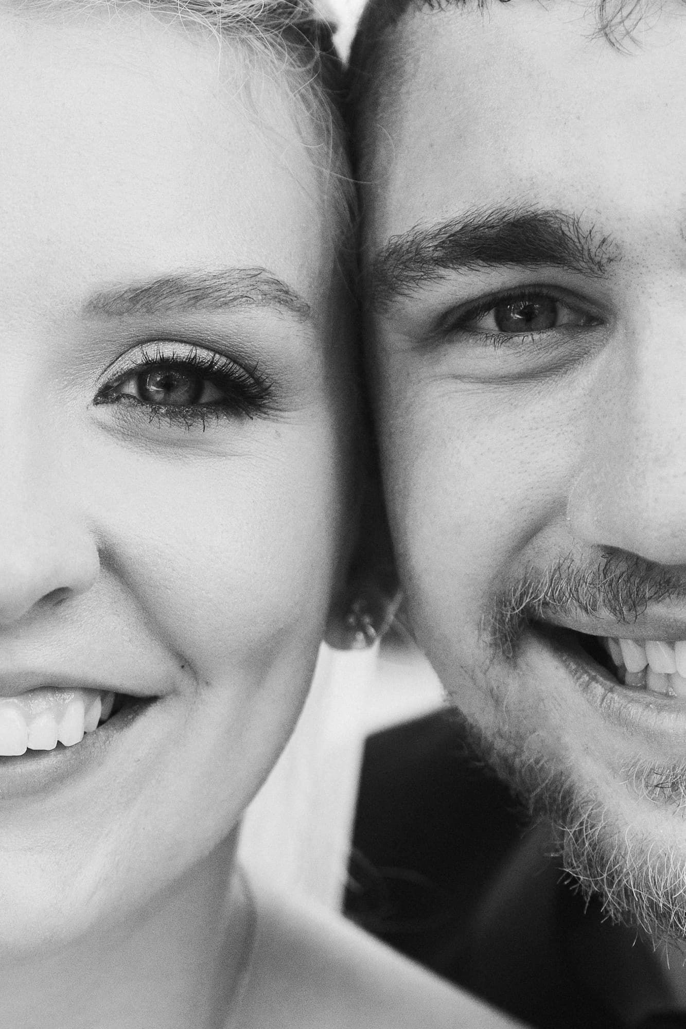 A close-up, black-and-white portrait of half of two smiling faces side by side.