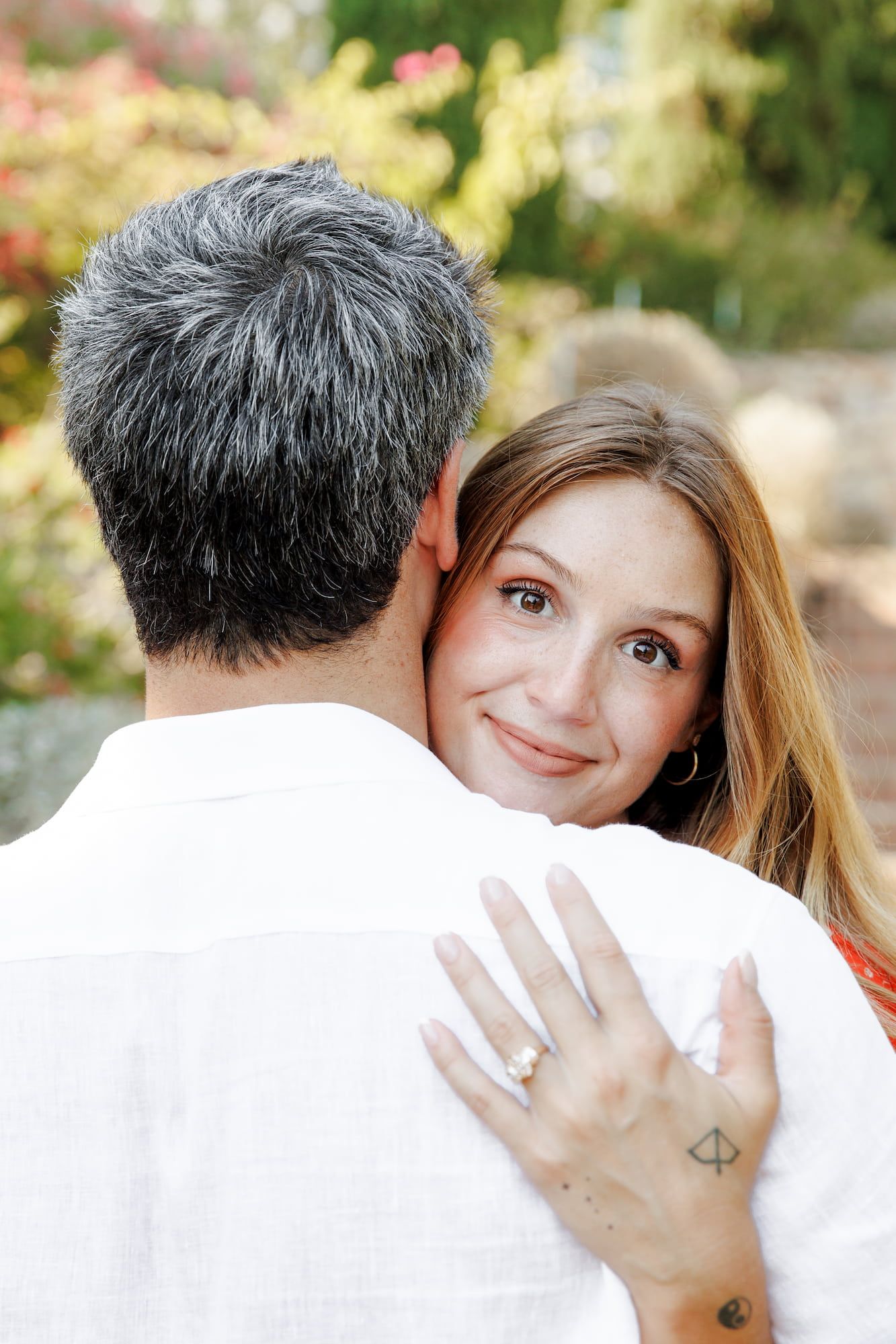 A woman with long hair hugs a gray-haired man after their surprise proposal in Barcelona