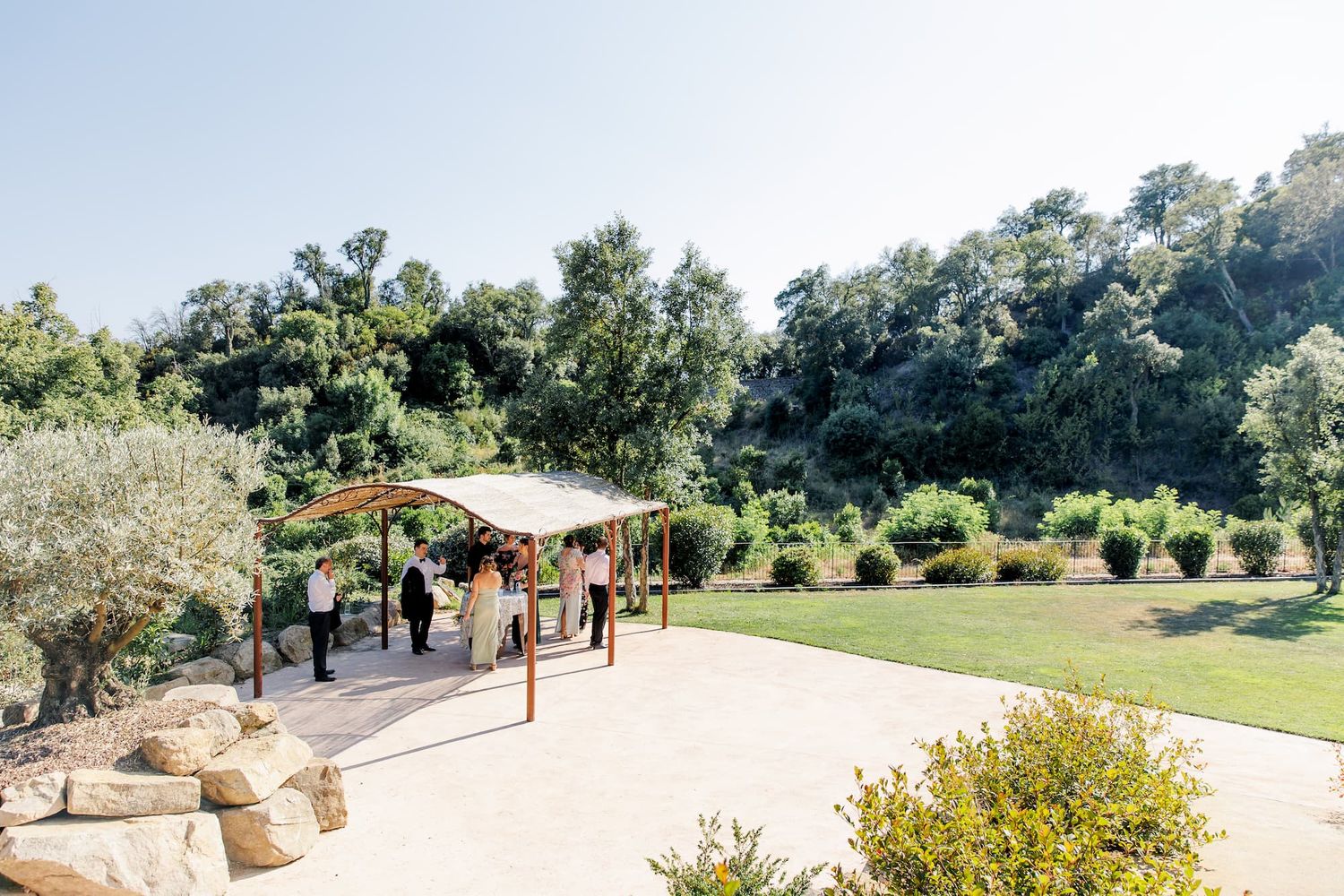 Scenic outdoor garden pathway with stone walls and lush greenery leading through a sunny Spanish landscape.