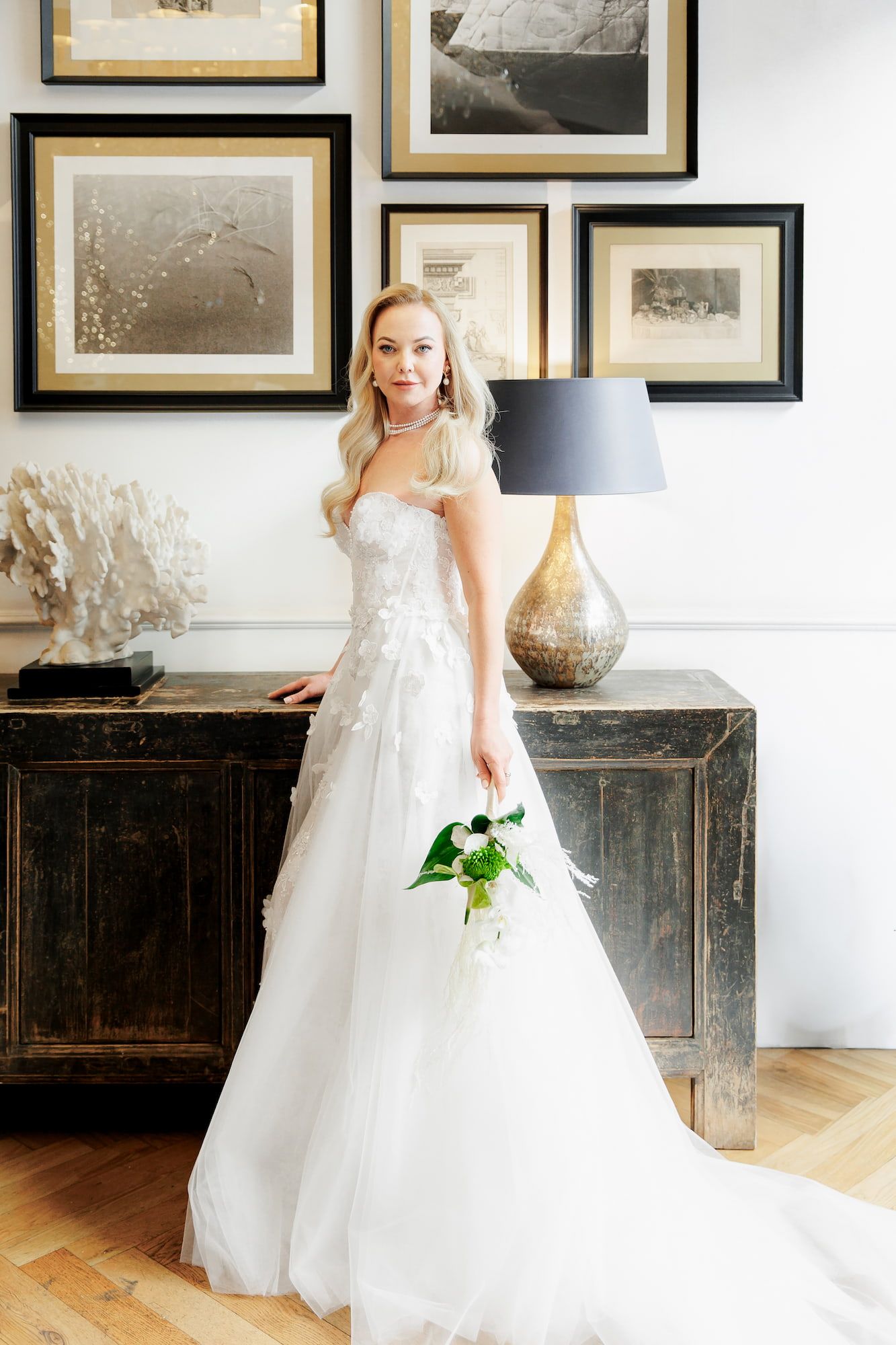 Bride in a white wedding gown holding flowers, looking straight at the camera