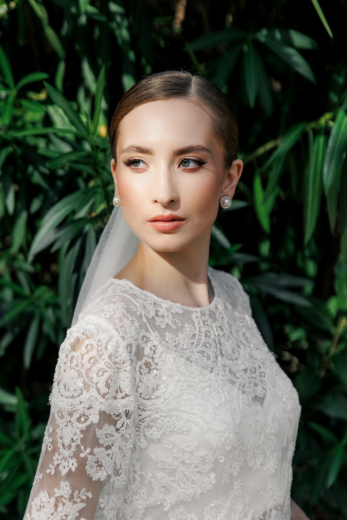 Elegant bride in white lace dress and veil poses to a wedding photographer in Barcelona