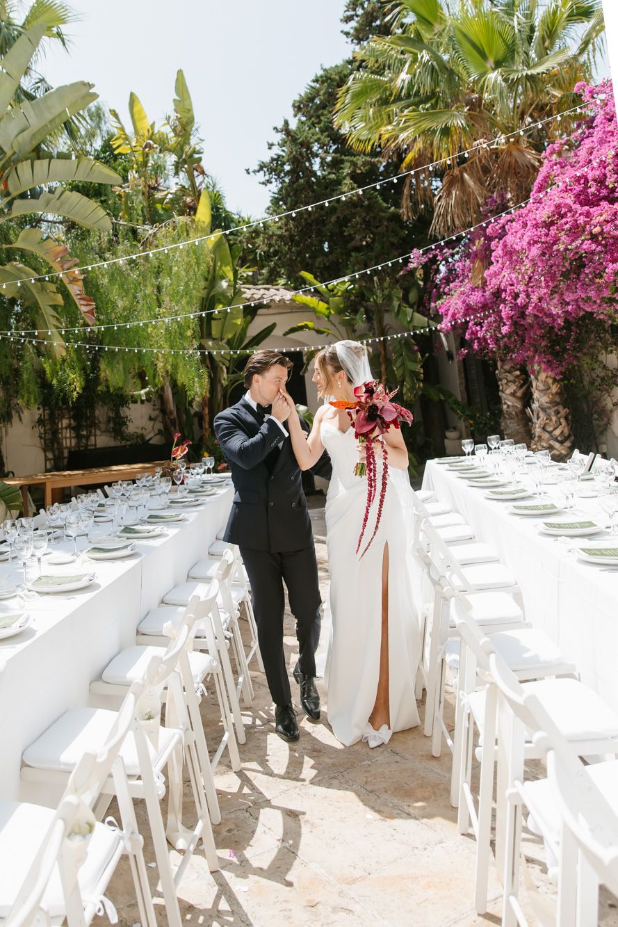 Bride and groom share a romantic moment between elegant white reception tables at Masia Victoria, Barcelona