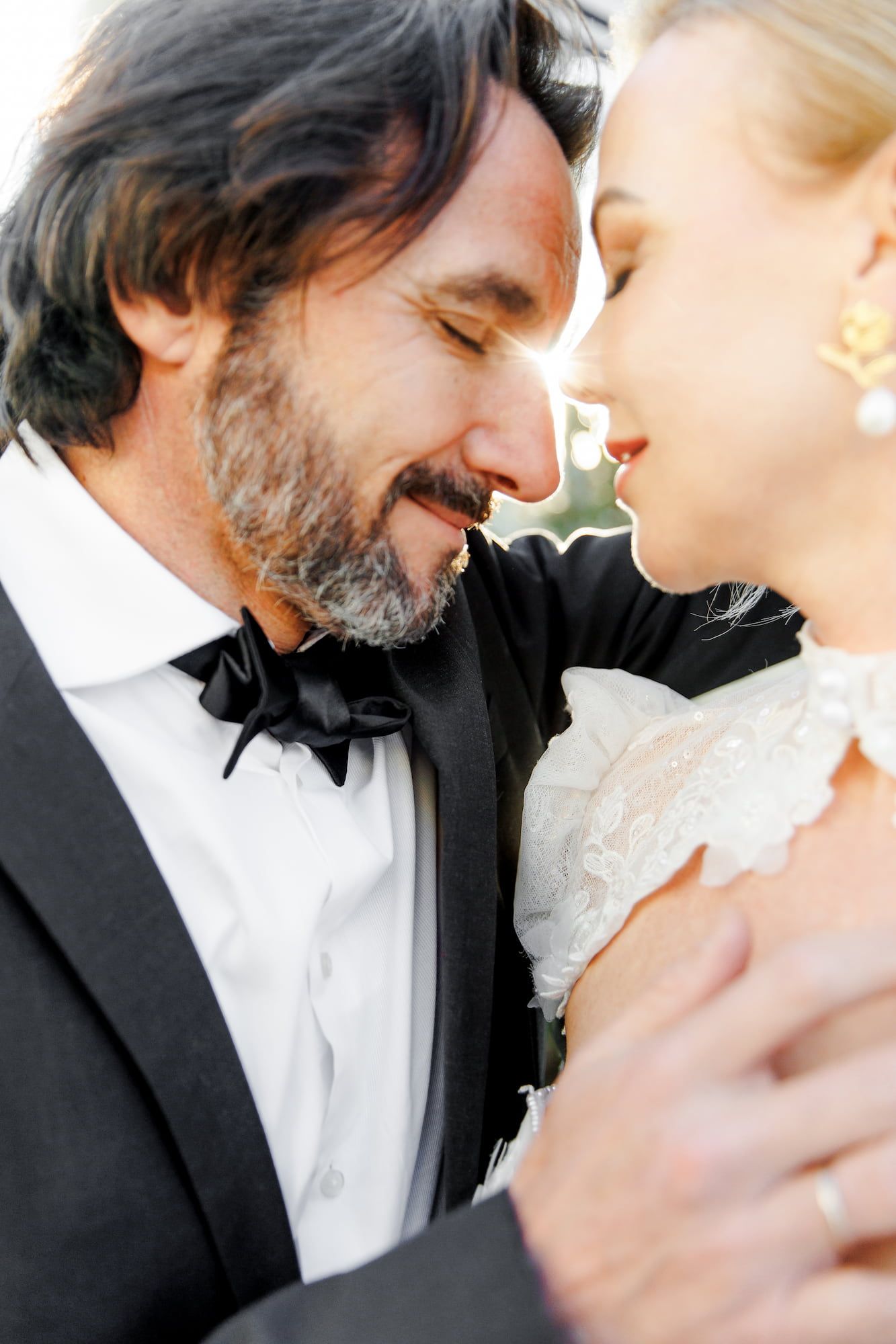 A close-up romantic moment between a couple in formal wedding attire.