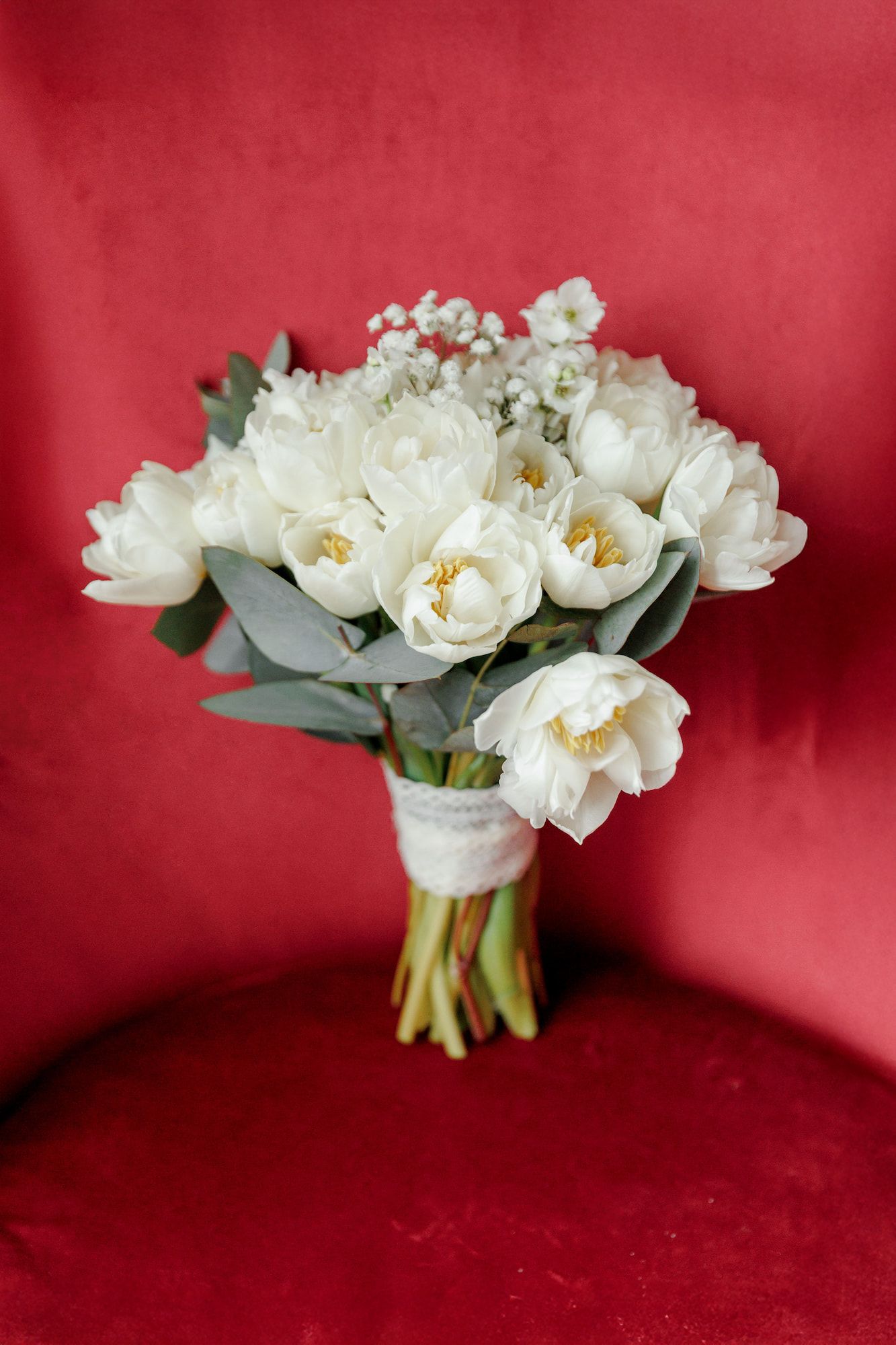 A bridal-style bouquet is staying on the red chair.