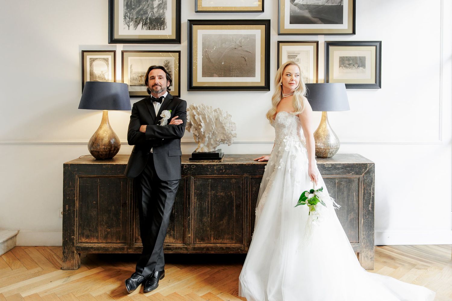 Bride in white wedding gown and groom in tuxedo pose casually at the hotel's lobby in Barcelona.