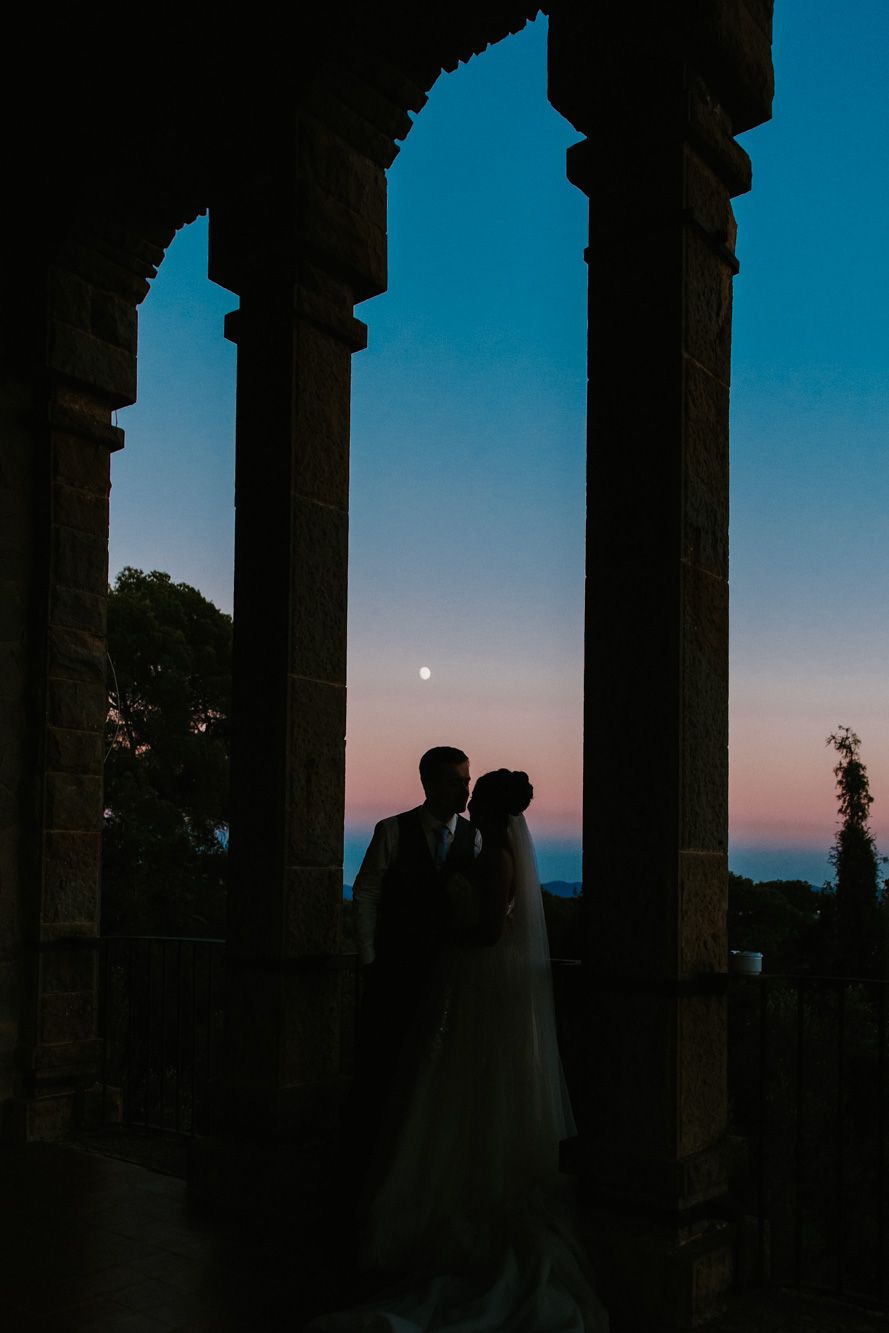 Silhouette of bride and groom kissing at the famoous balcony at La Baronia wedding venue.