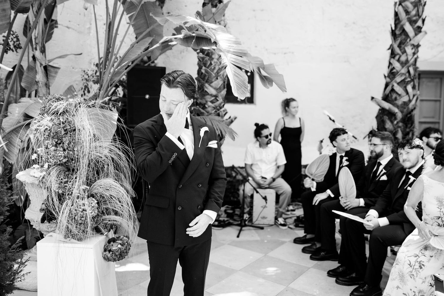 The emotional groom wipes tears at the wedding ceremony before seeing the bride.