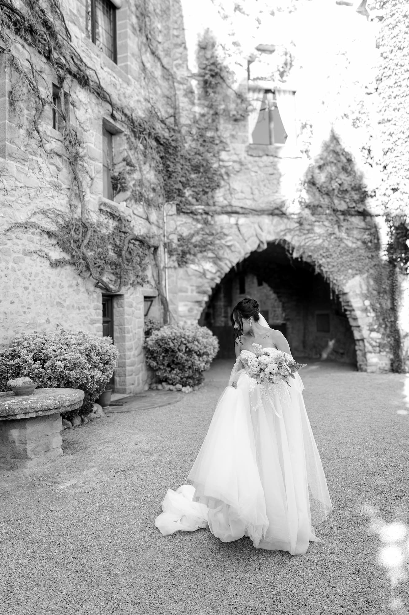 Editorial portrait of a bride walking in front of the facade of the best wedding venue in Spain, La Baronia.