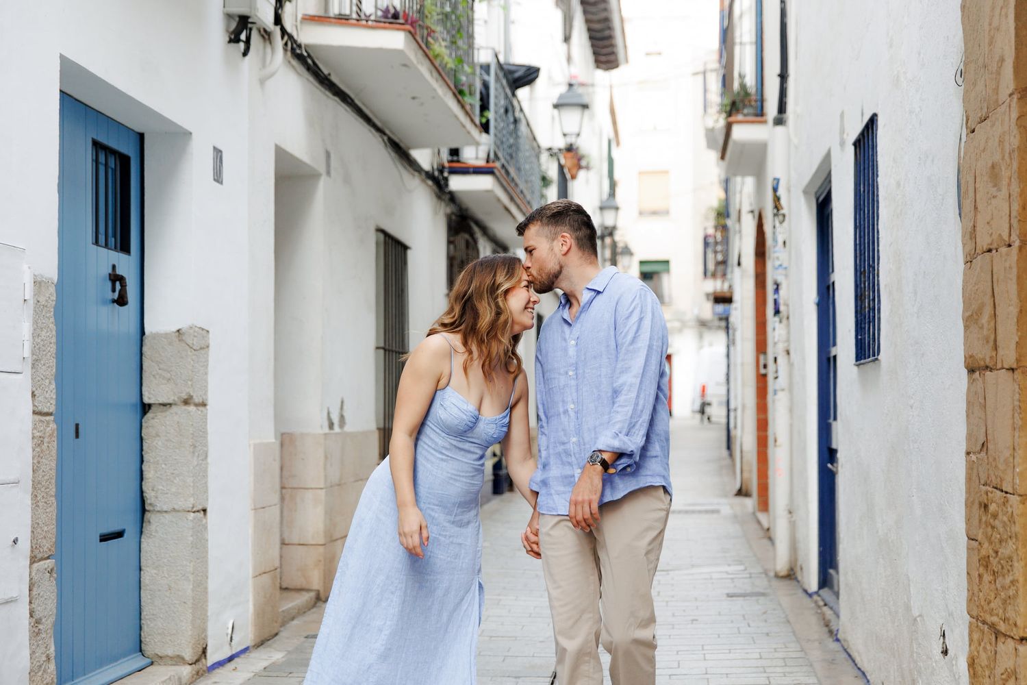An engaged couple walking among the streets of Sitges, dressed up in blue matched clothes