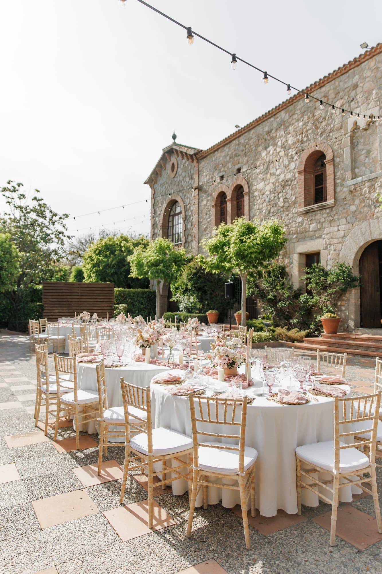 Elegant outdoor wedding reception at Mas de Sant Lleí with chiavari chairs, white tablecloths, and floral centerpieces.