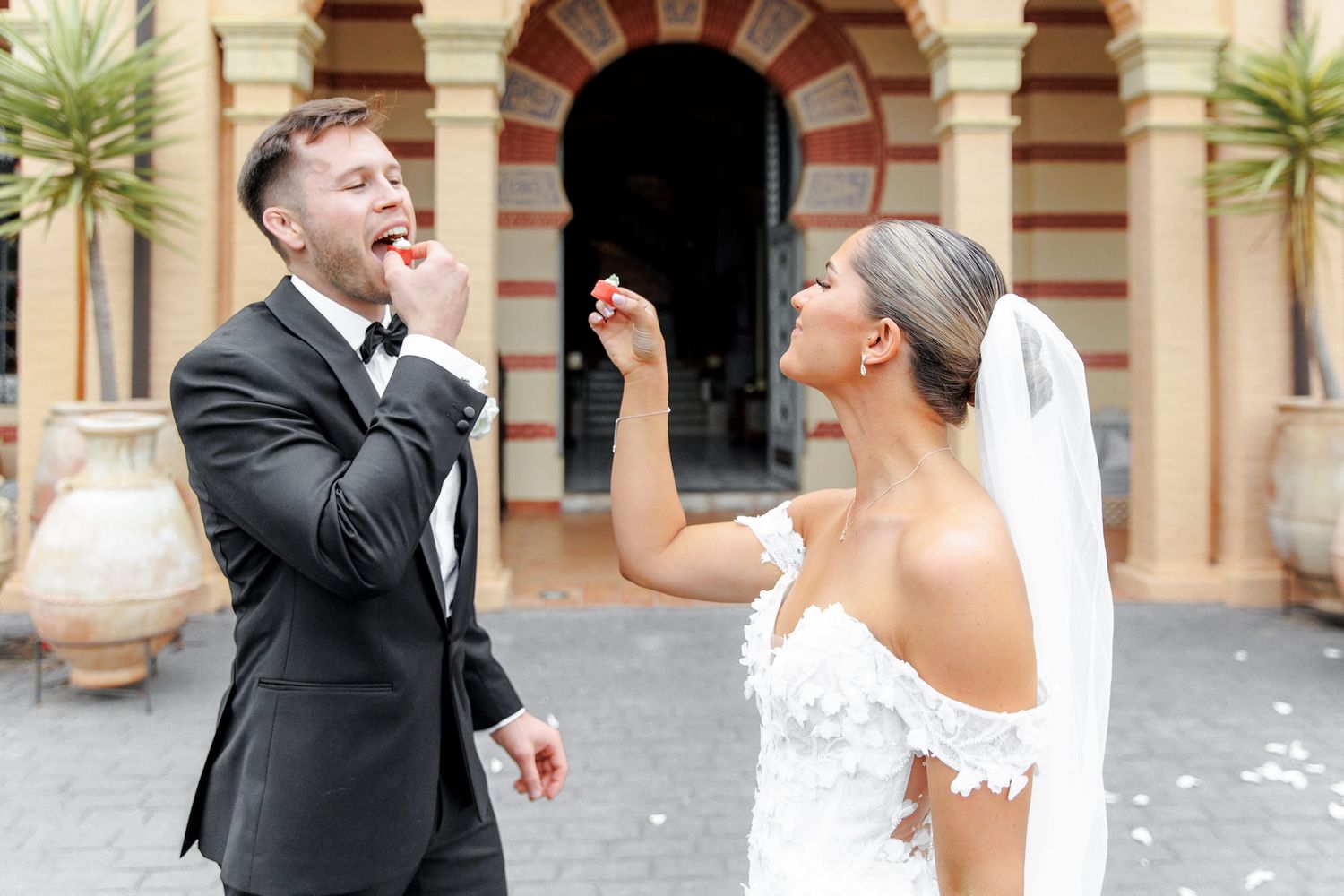 Bride and groom laughing and sharing a sweet moment outside a historic venue on their wedding day.