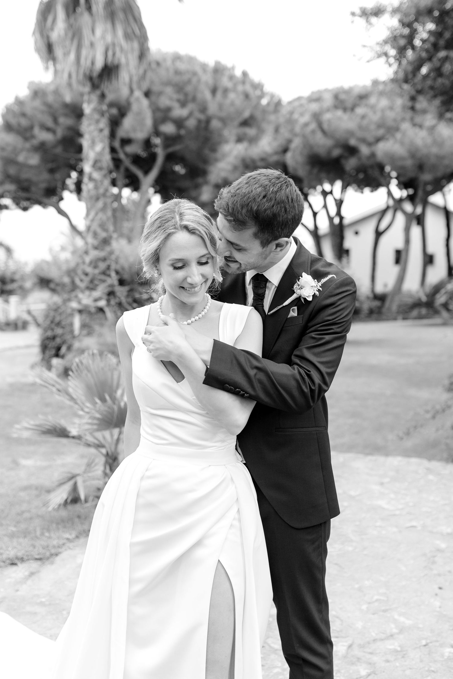 The bride and the groom embrace each other in the garden of the wedding venue in Barcelona