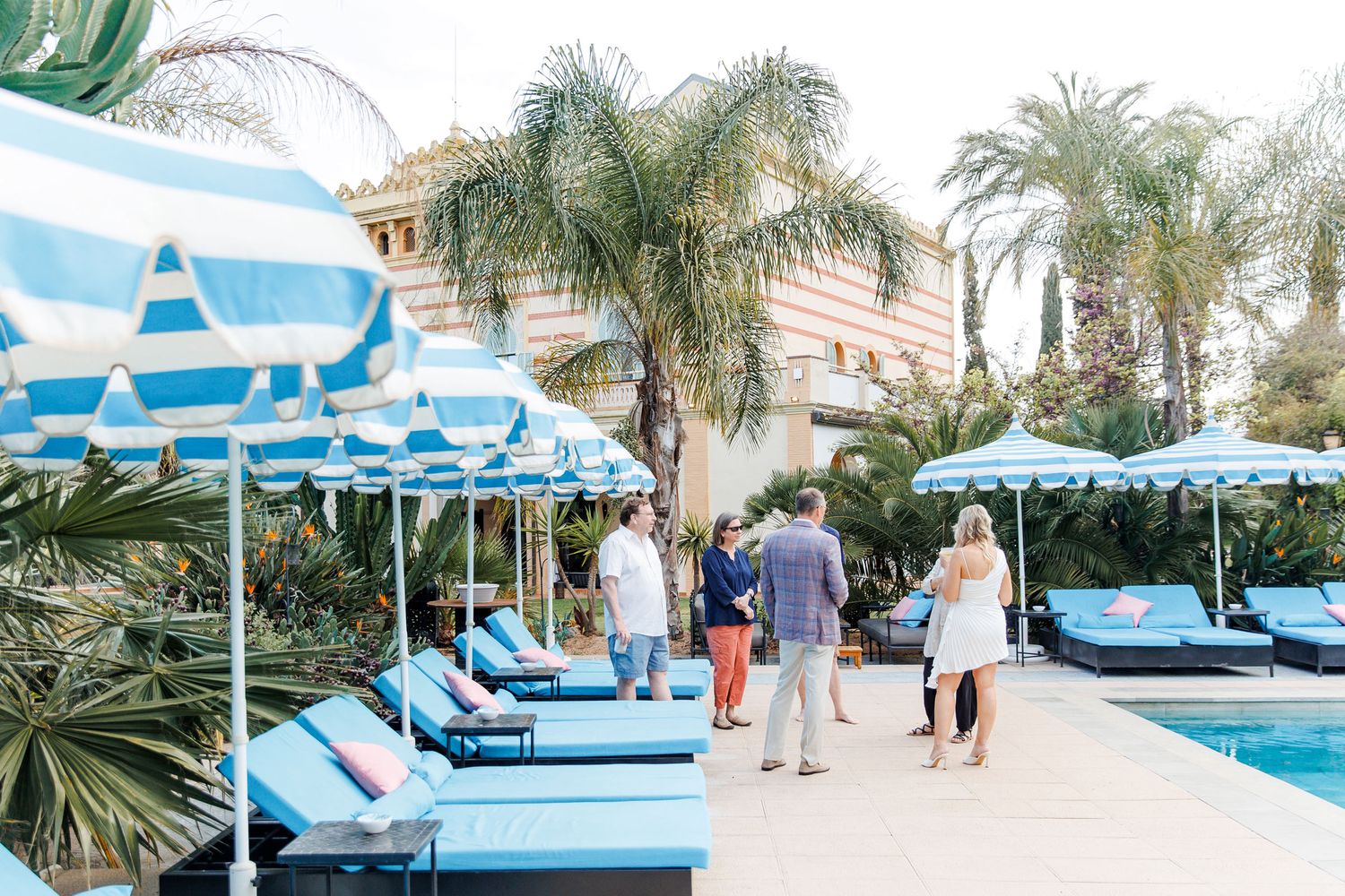 Guests enjoying an outdoor rehearsal dinner next to the pool with blue water