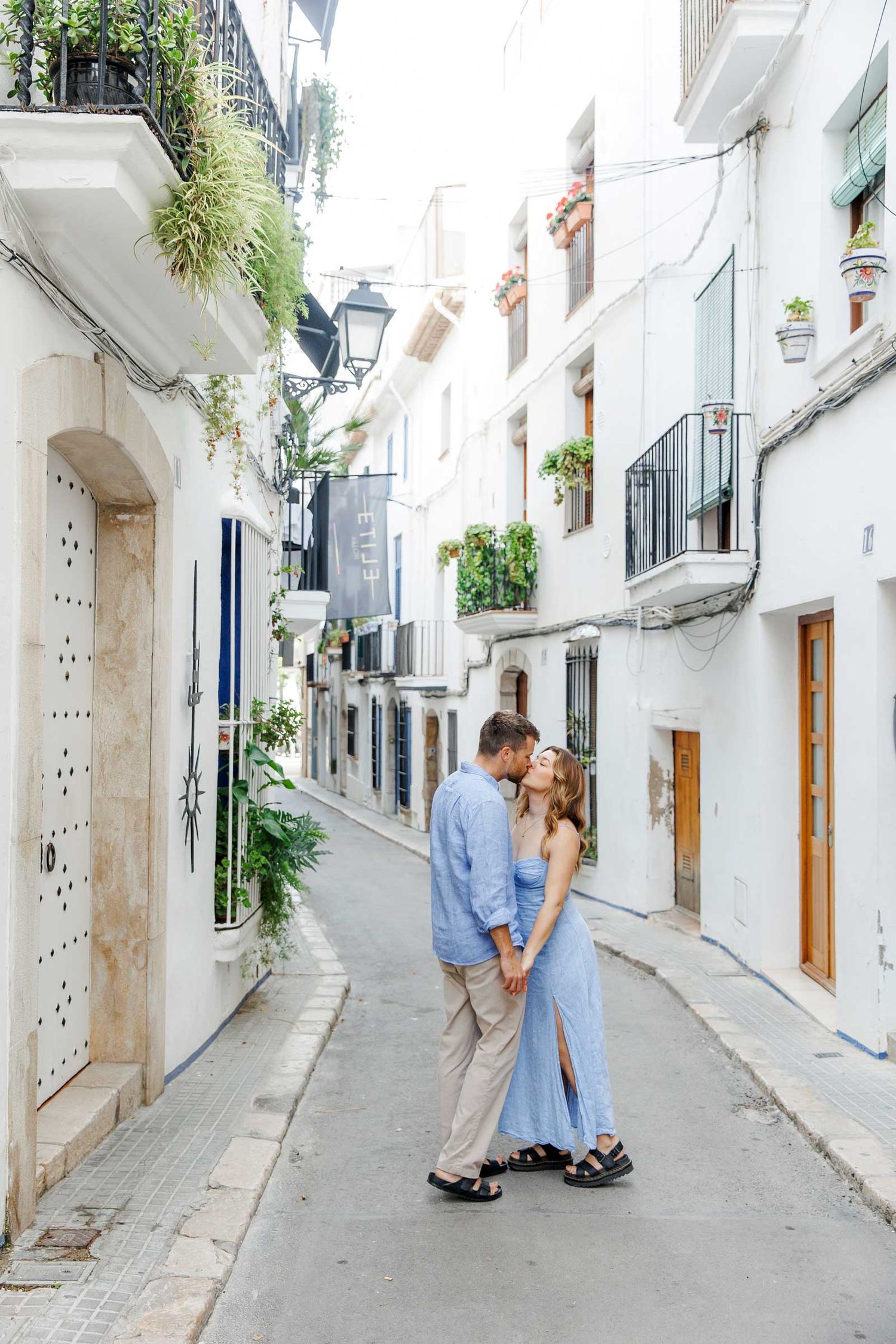 A couple in blue clothes kissing in the streets of Sitges, Barcelona