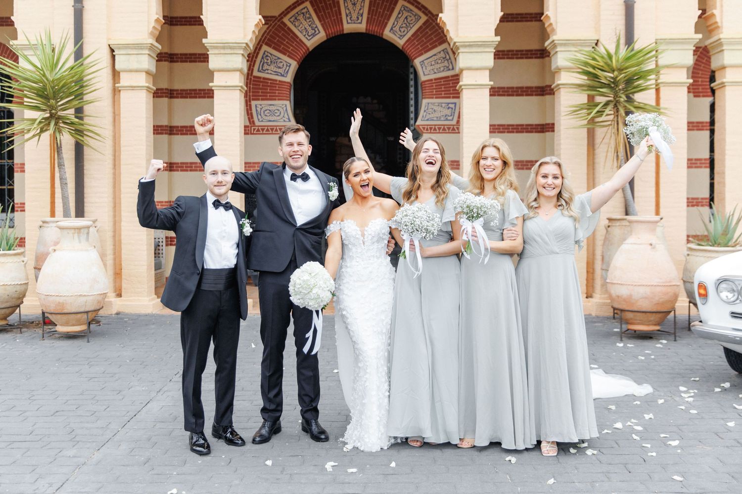 The wedding party is enjoying the time during the wedding. The bridesmaids wear matching green dresses and the groom wears black attire.