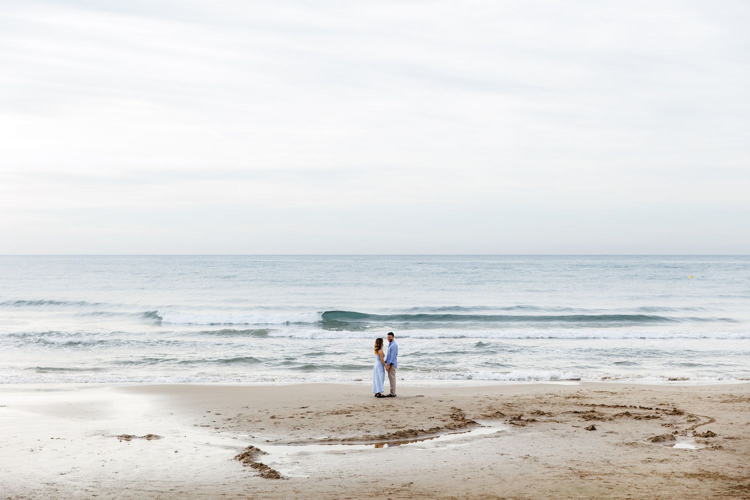 An engaged couple looking at the blue sea water