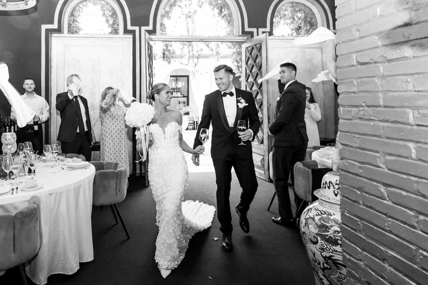 The groom and the bride are entering the reception area while dancing and greeting all the guests
