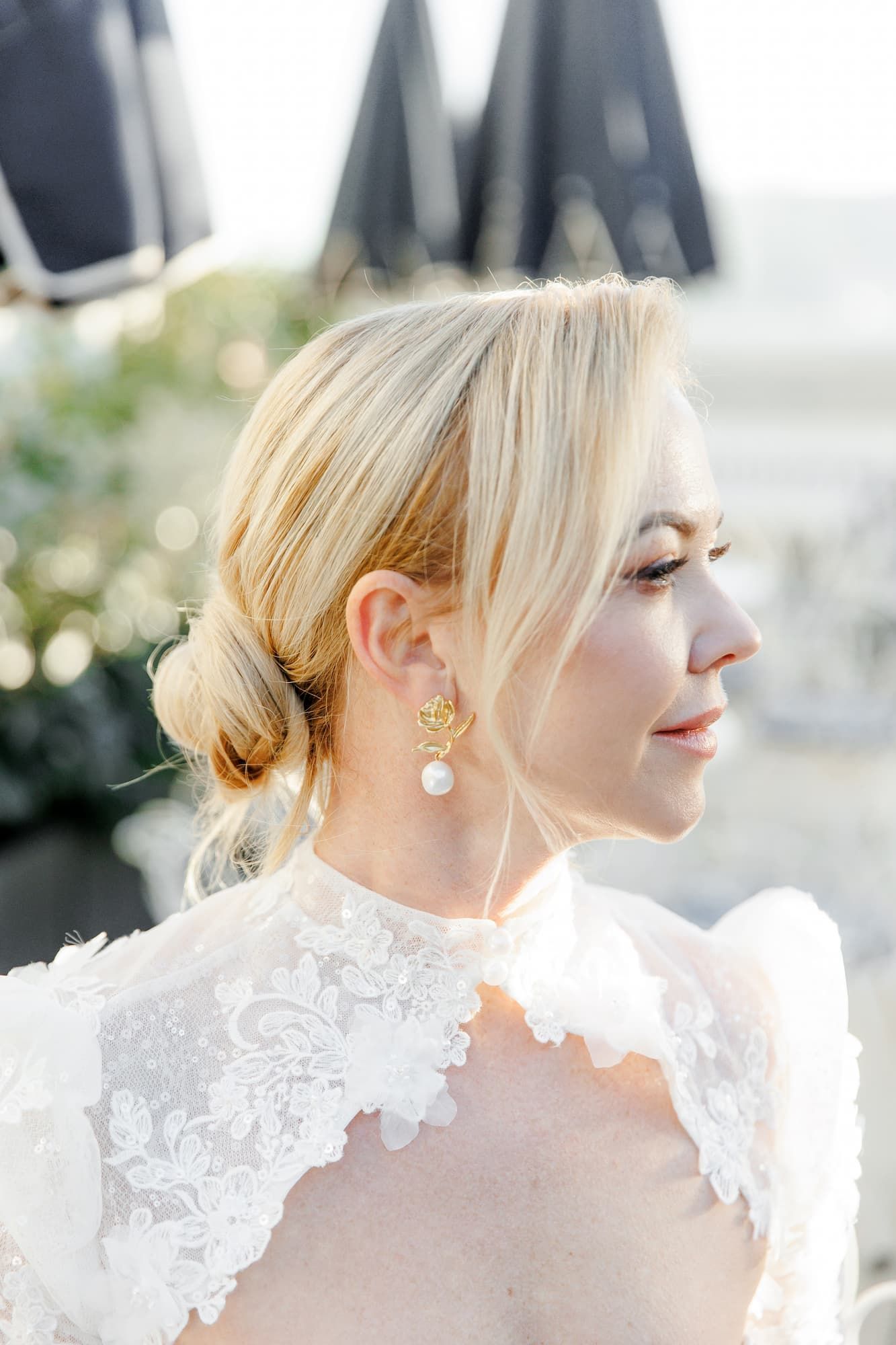 Close-up profile view of a bride wearing an elegant white lace wedding dress with pearl earrings.