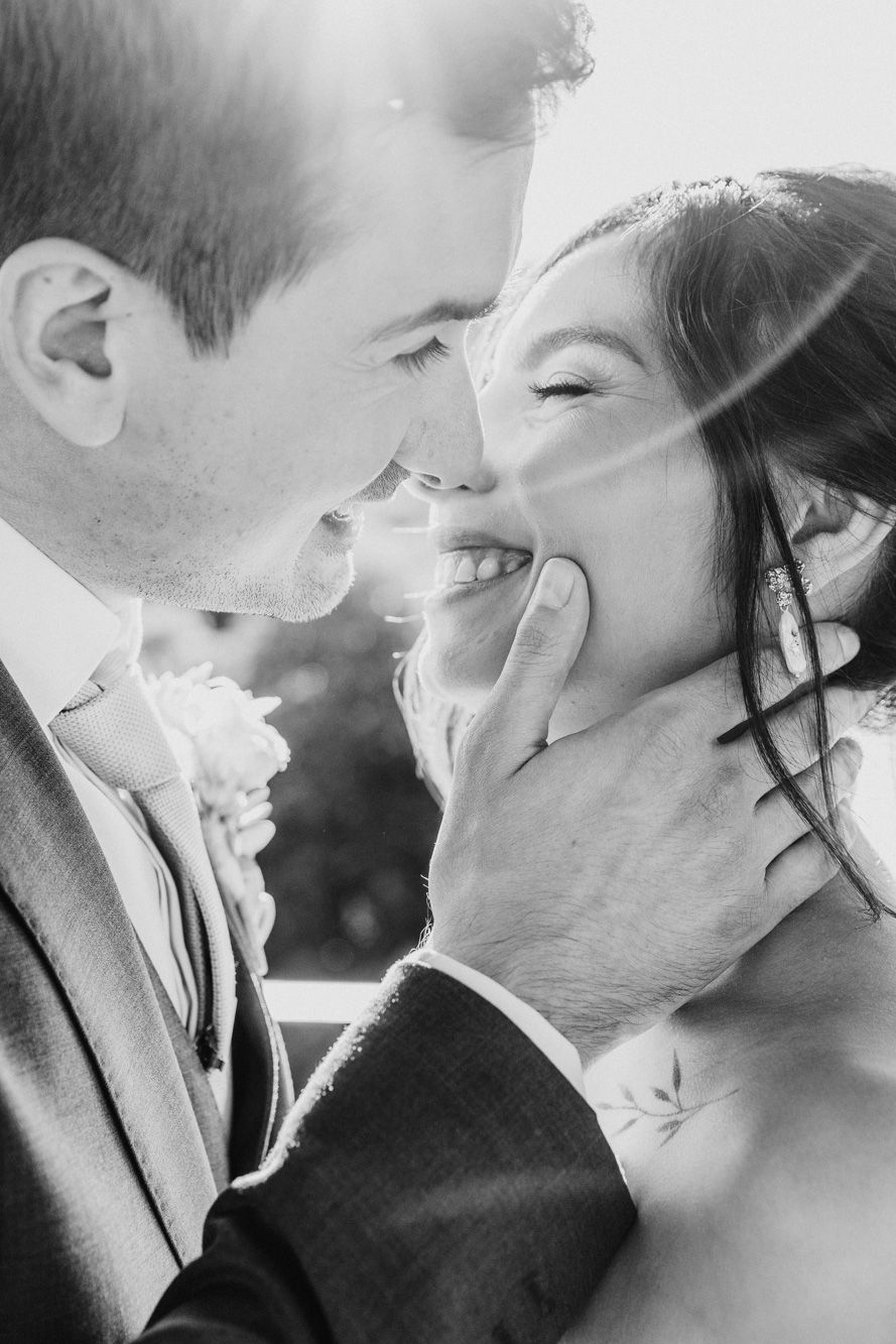 Black and white wedding photo of groom tenderly cupping brides face as they share a romantic moment.