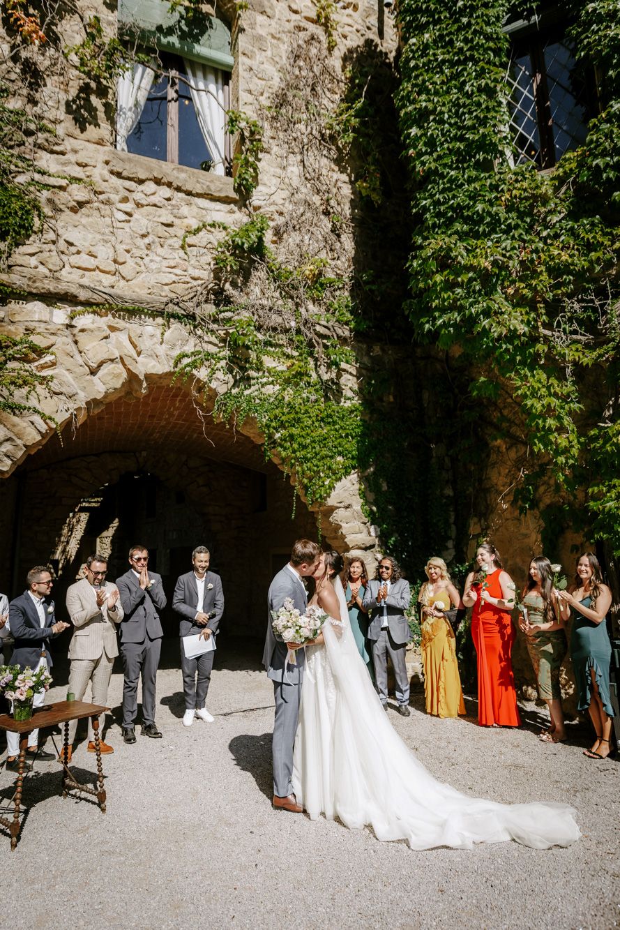 Bride and groom share first kiss at outdoor wedding ceremony before guests at La Baronia.