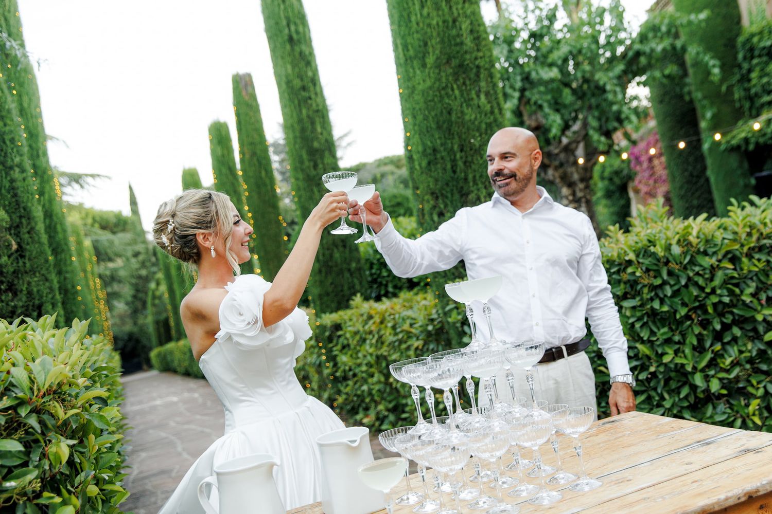 Bride and groom toasting champagne glasses outdoors at wedding reception in Barcelona.