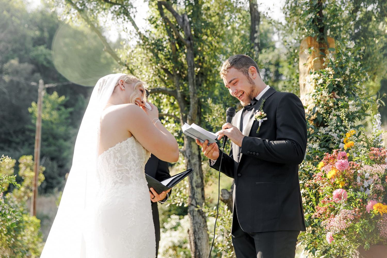 A couple shares intimate moments during an outdoor garden wedding ceremony surrounded by blooming flowers and trees.
