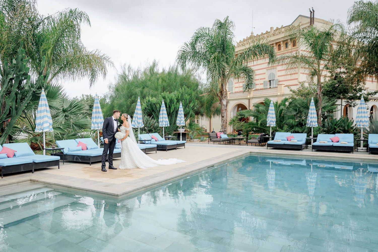 The couple in the wedding attire posing next to the swimming pool during there wedding at Gran Villa Rosa in Barcelona