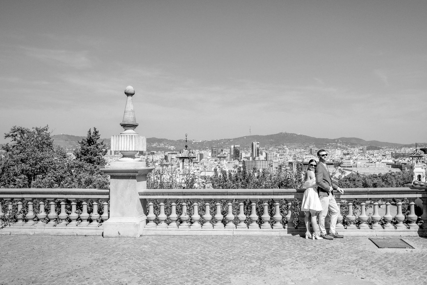 The bride holds the groom from behind as they enjoy the view of Barcelona.