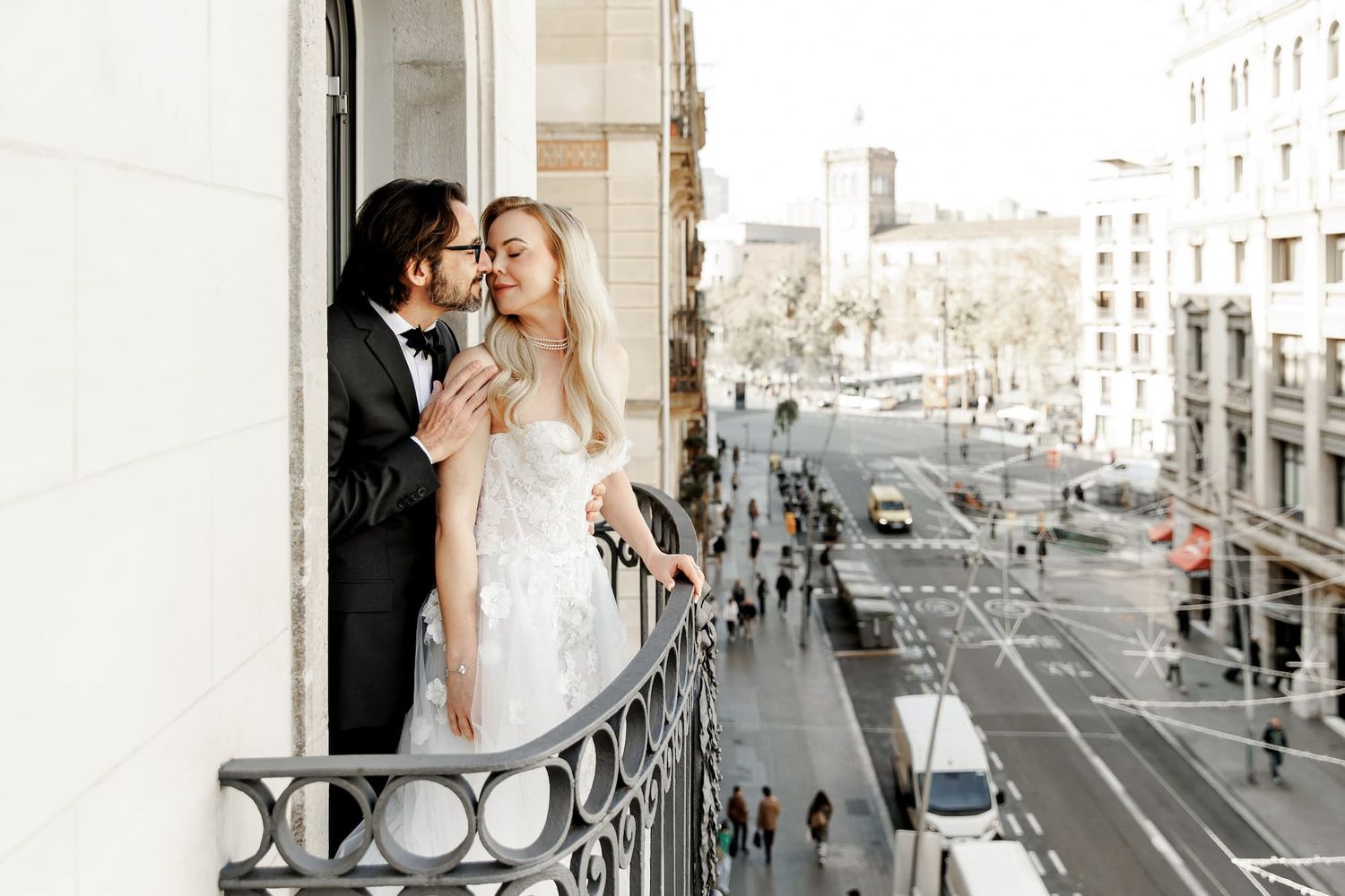 An editorial photo showing the couple in elegant attire against urban architecture and the streets of Barcelona