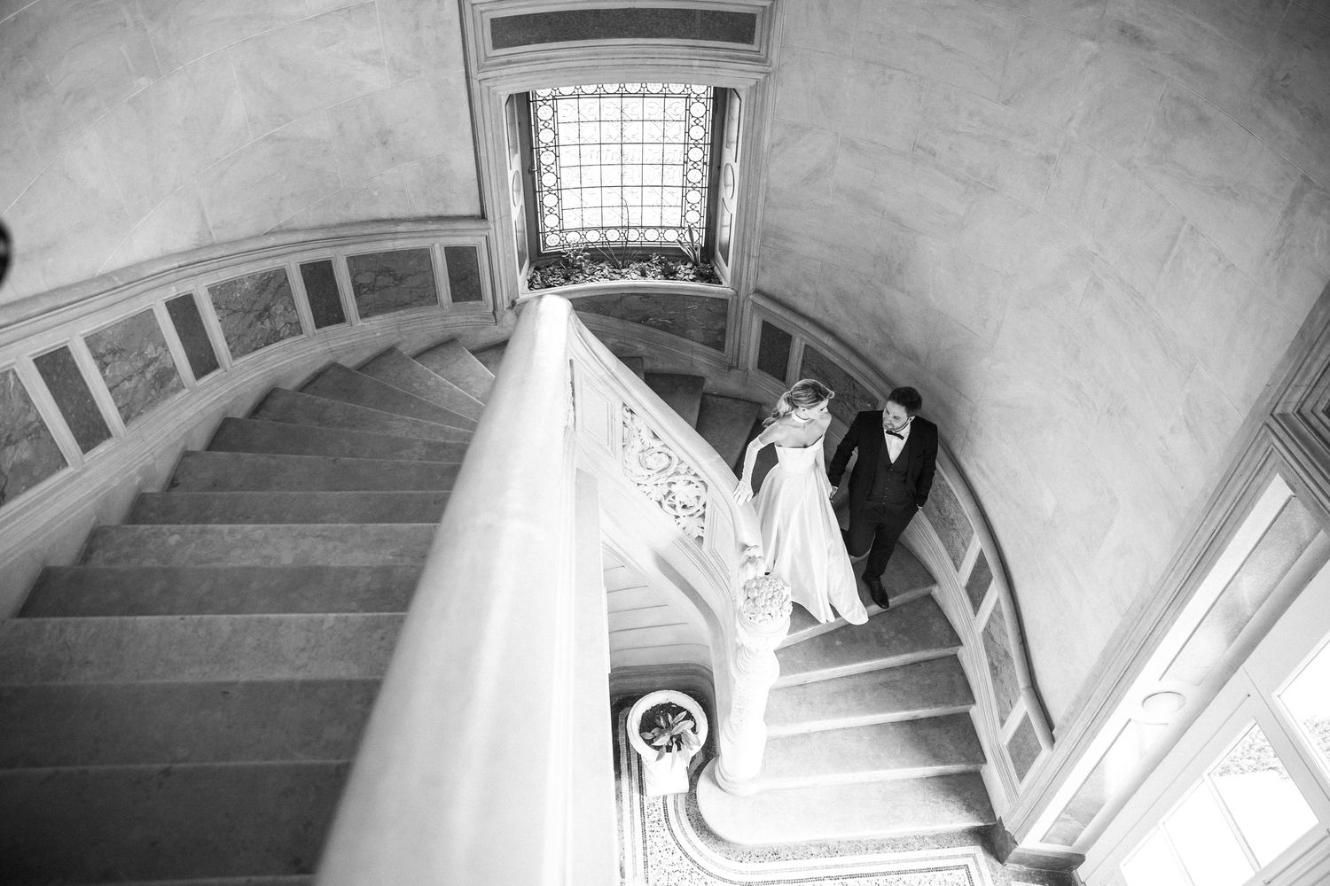 A candid moment of a couple walking down the staircase in a sophisticated French chateau.