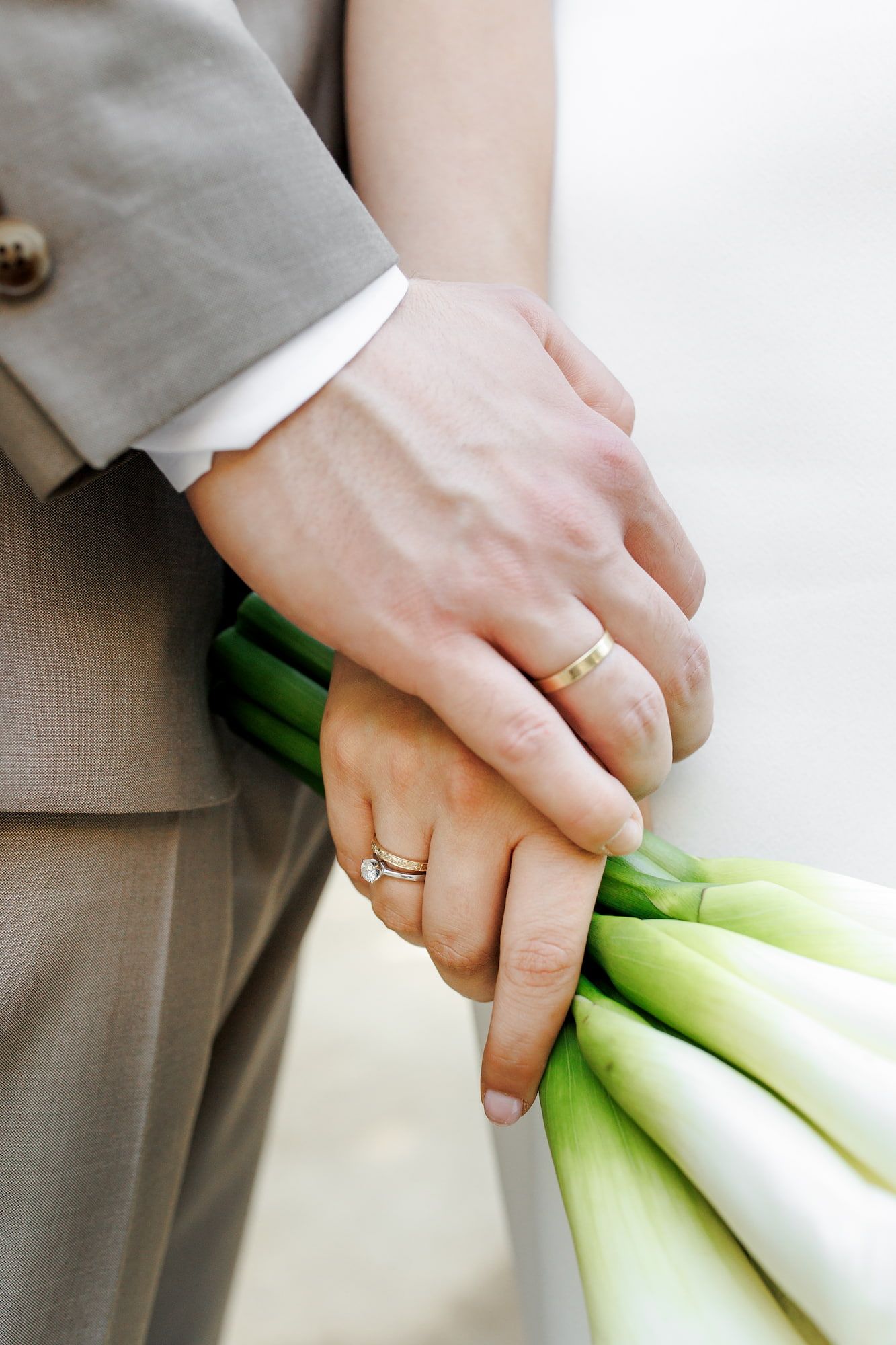 Close-up view of hands chopping fresh green leeks on a light colored surface.