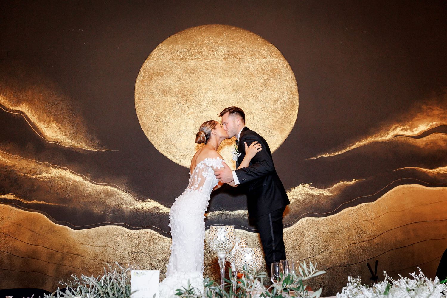 A romantic couple kisses in front of a dramatic full moon during their wedding in Barcelona