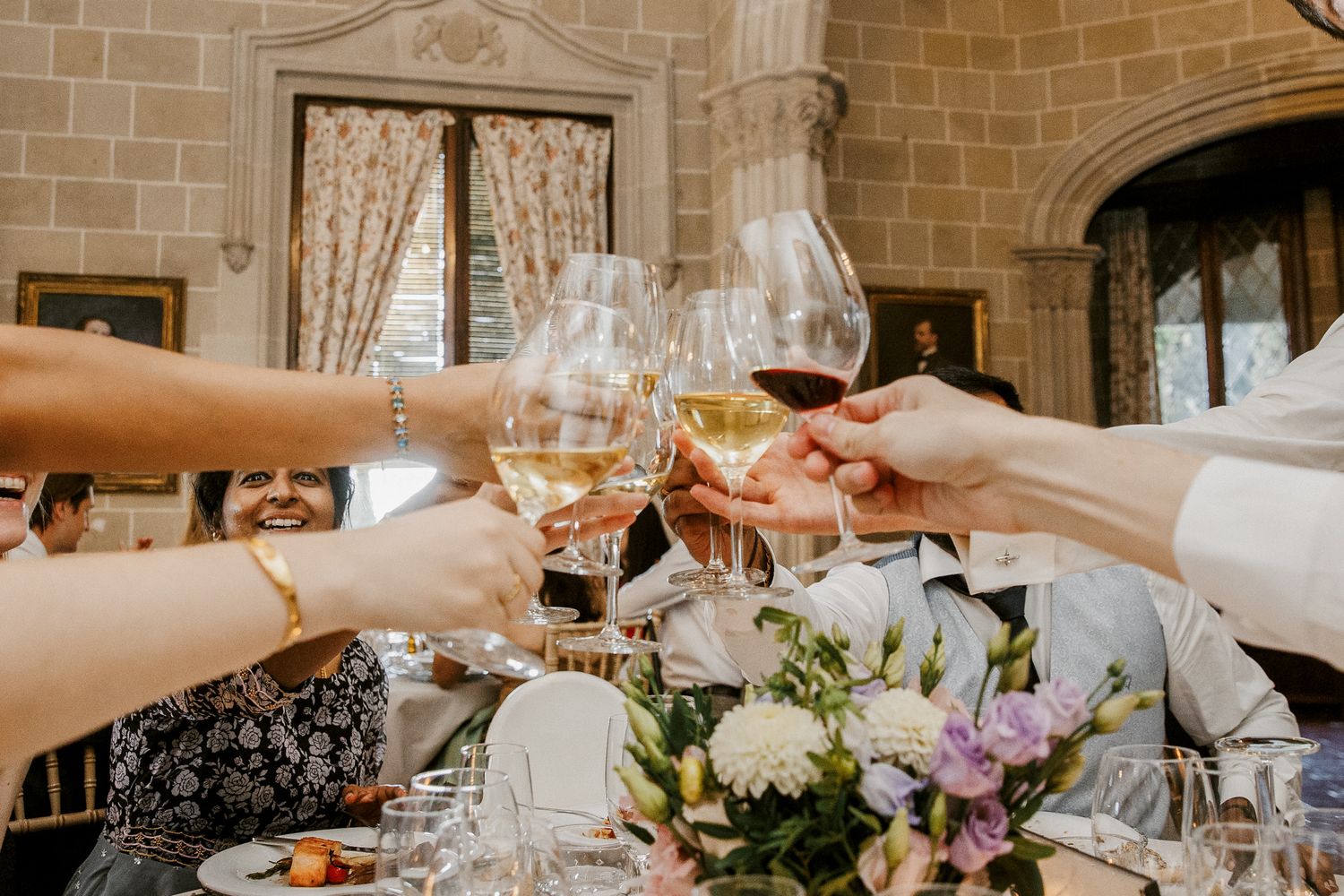 Guests raising wine glasses in a toast at an elegant wedding reception  | La Baronia | Wedding Photographer Barcelona | Spain Wedding Venue