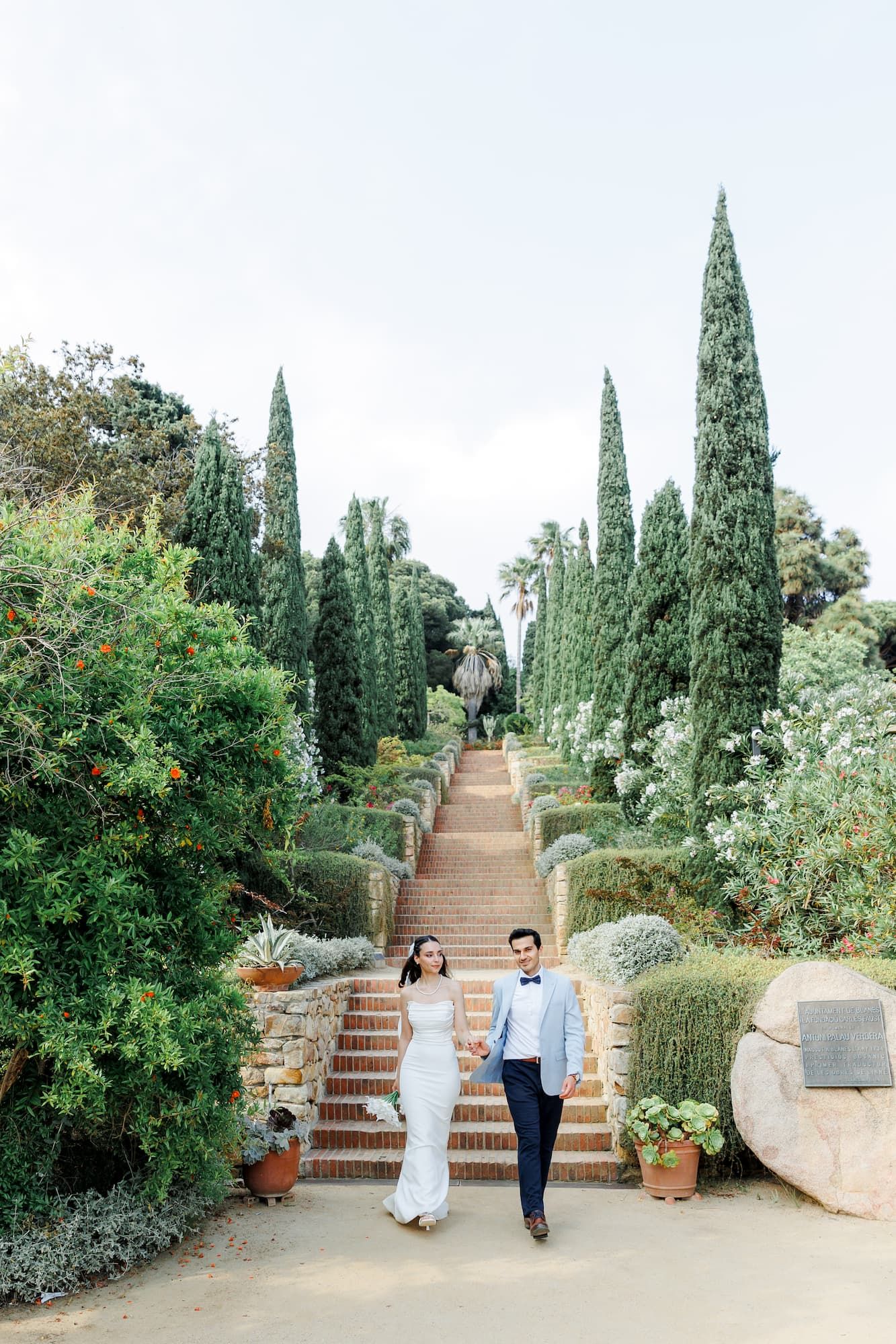 A stone stairway lined with trees and Mediterranean landscaping leads upward through a scenic Marimurtra Garden in Barcelona