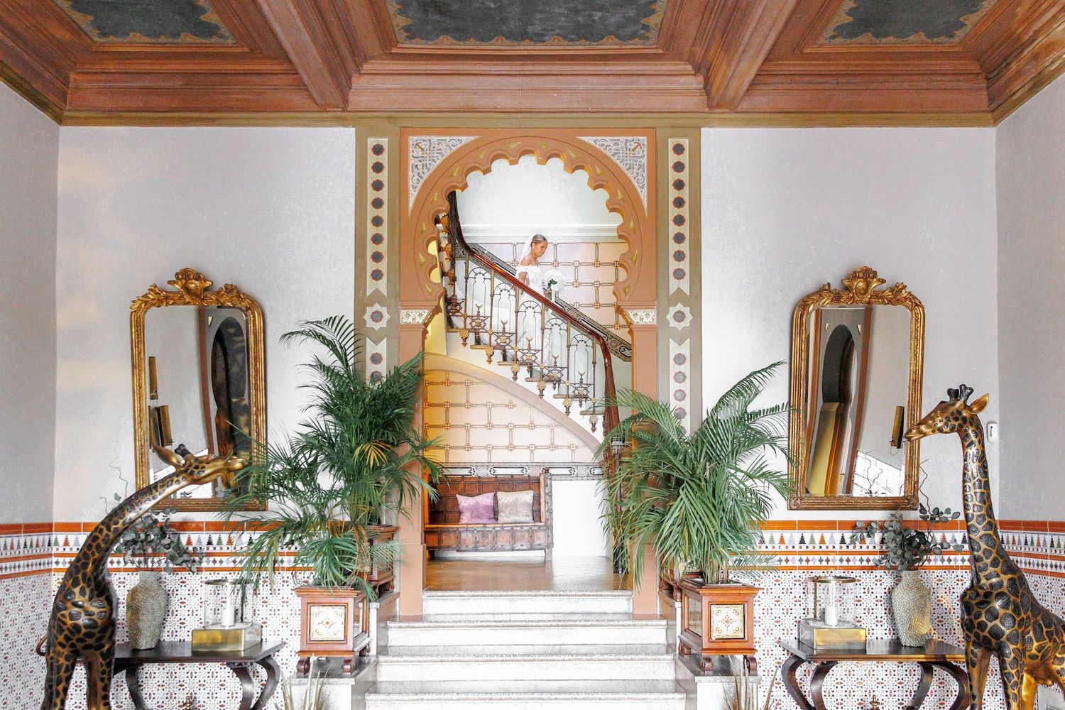 The dressed bride is going down the stairs to see her fiancé for the first time. First look in Barcelona.