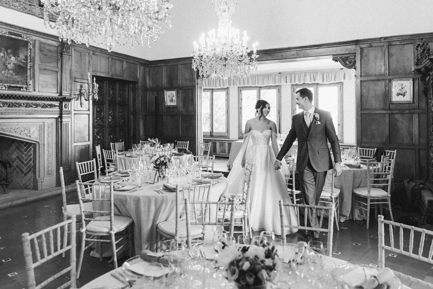 The groom and the bride walking among tables prepared for the wedding dinner in the luxury wedding venue in Barcelona.