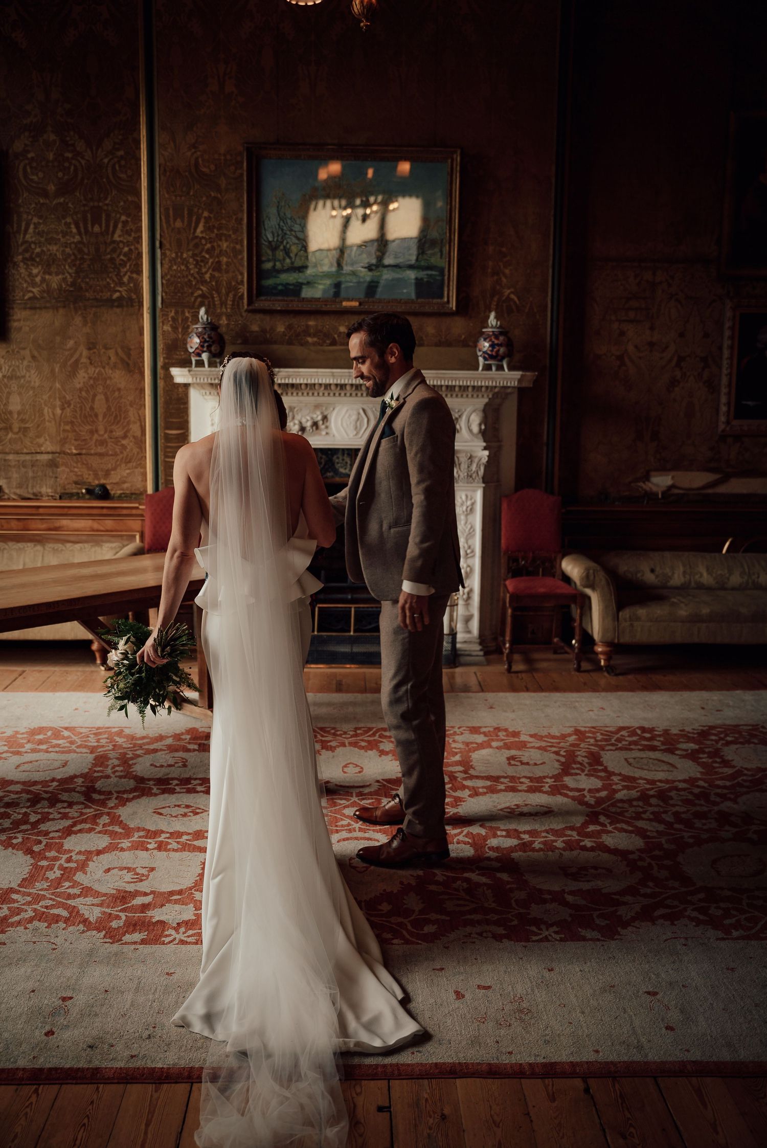 Wedding ceremony in an ornate historic room with red carpet and dramatic lighting.