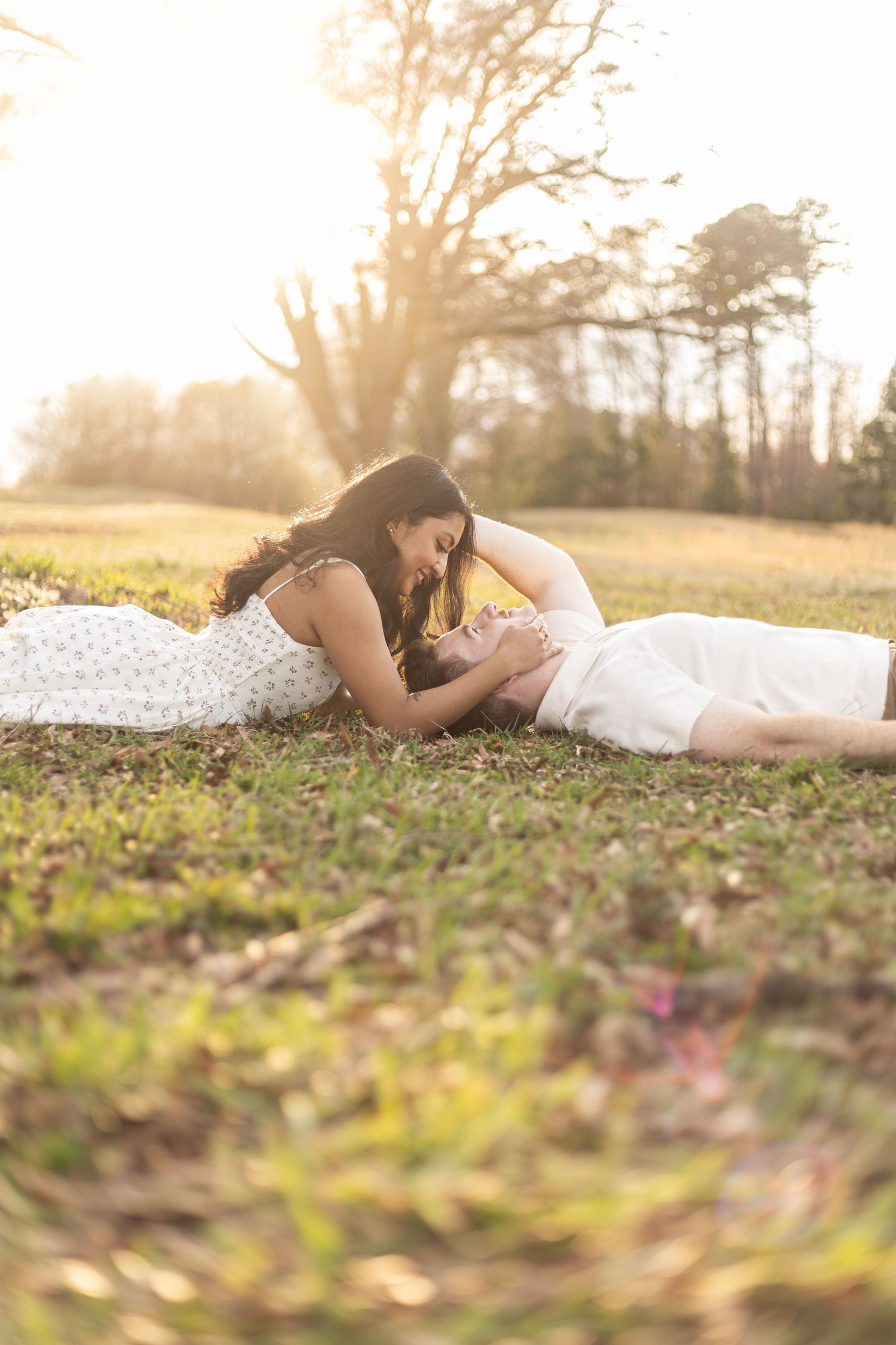 Couple lying together on autumn ground during sunset photoshoot.