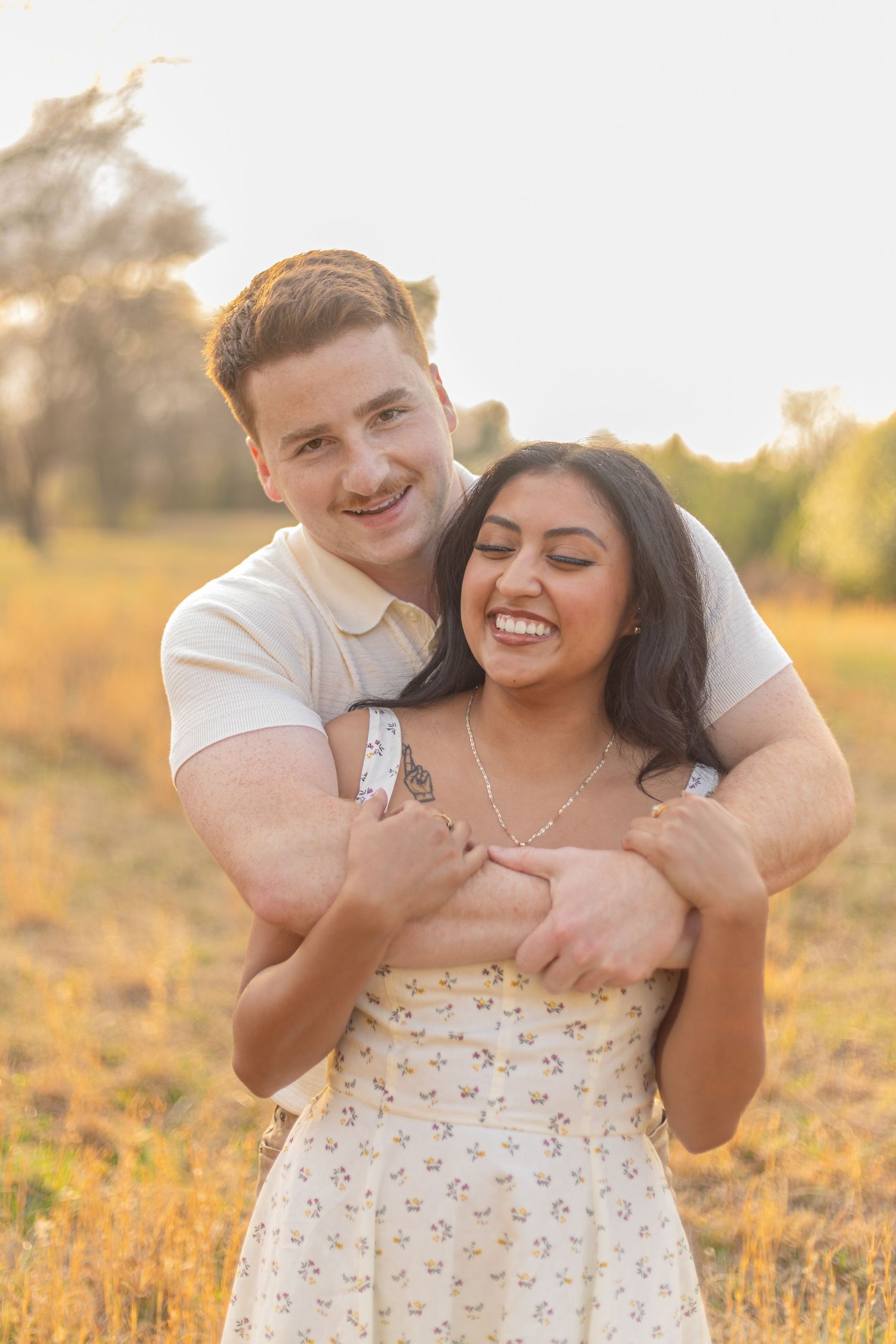 A romantic couple shares tender moments in a sunlit field during golden hour.