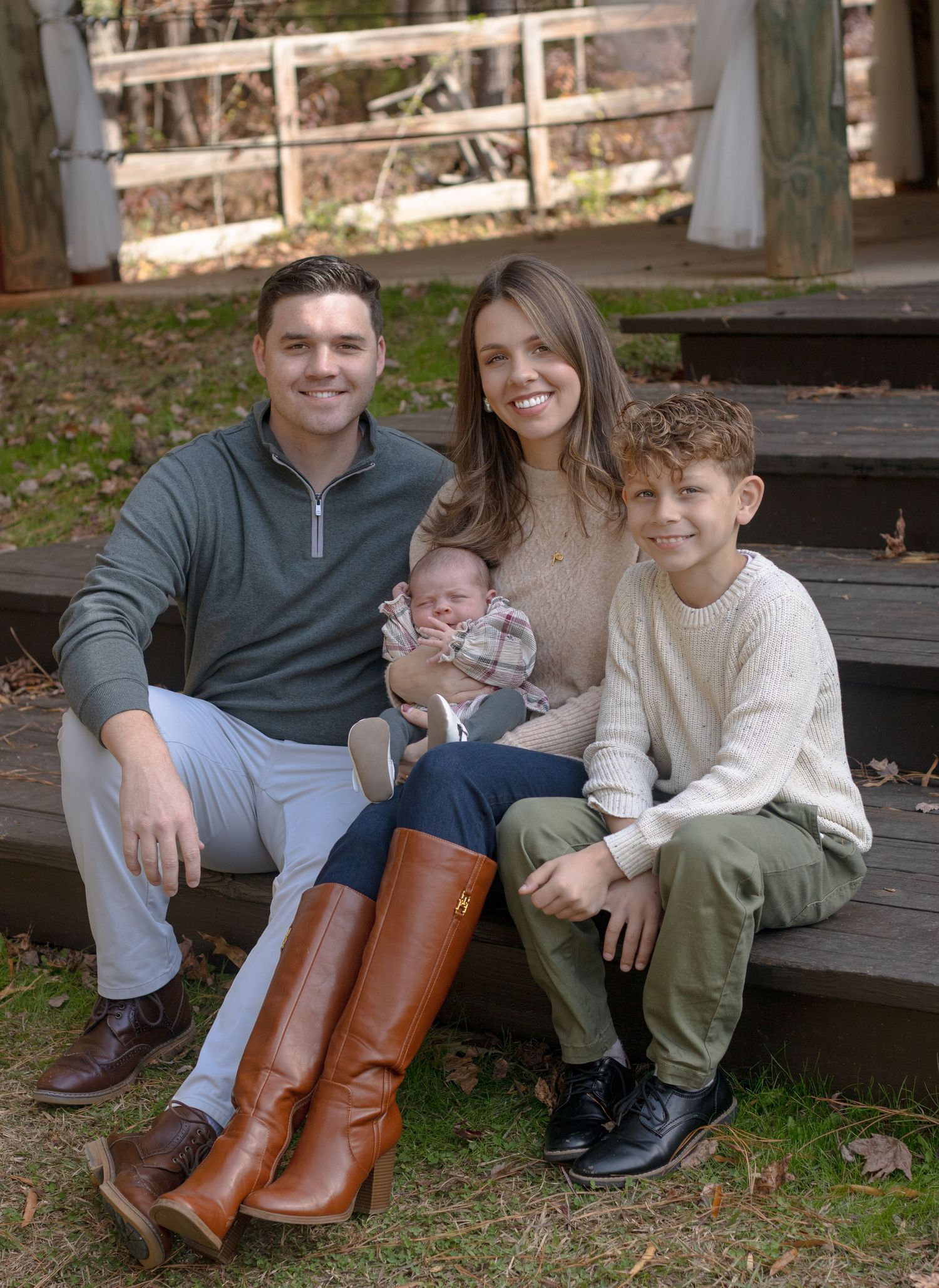 Family sitting on wooden bench in casual attire during autumn photo session.