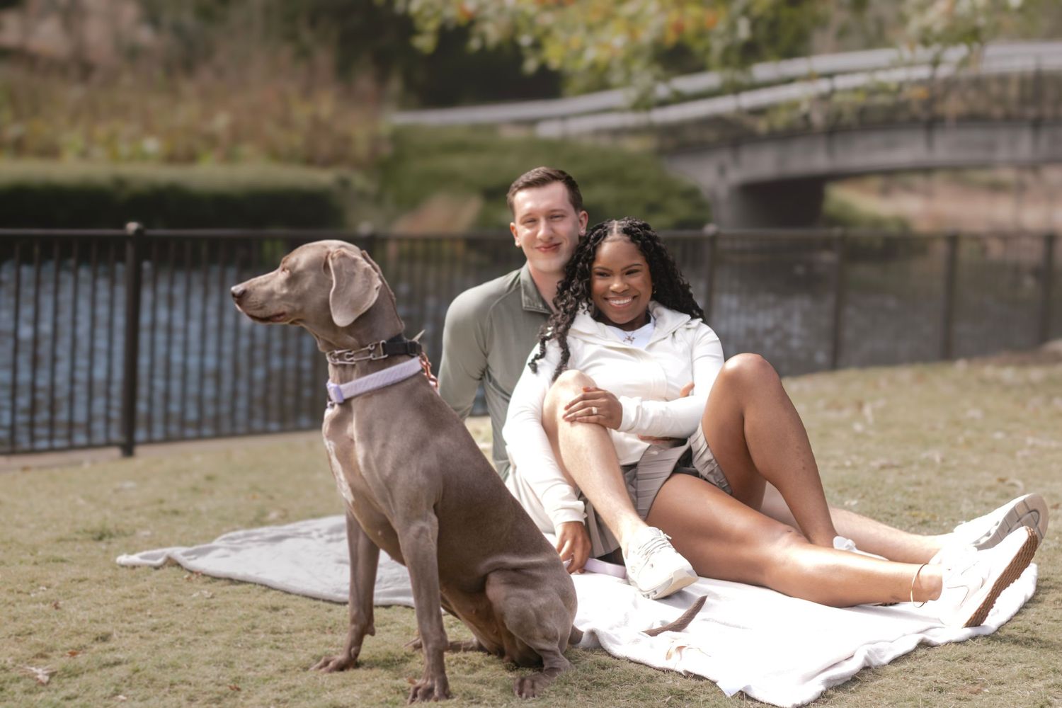 Person in white dress relaxing outdoors with their gray dog.