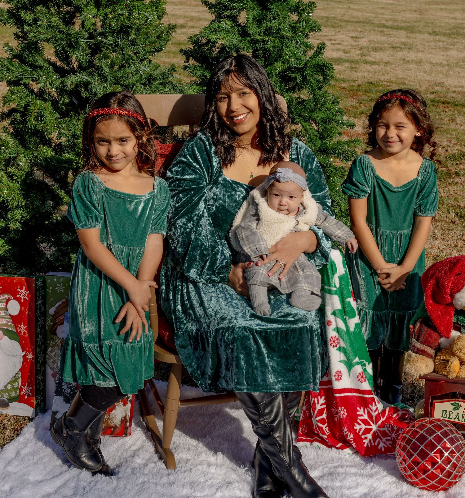 Holiday portrait with group in green velvet dresses seated by Christmas tree with presents.