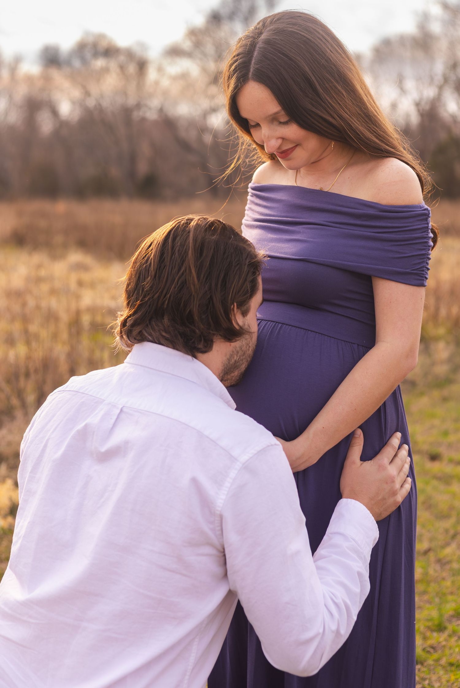 Tender moment between couple during outdoor maternity photoshoot.