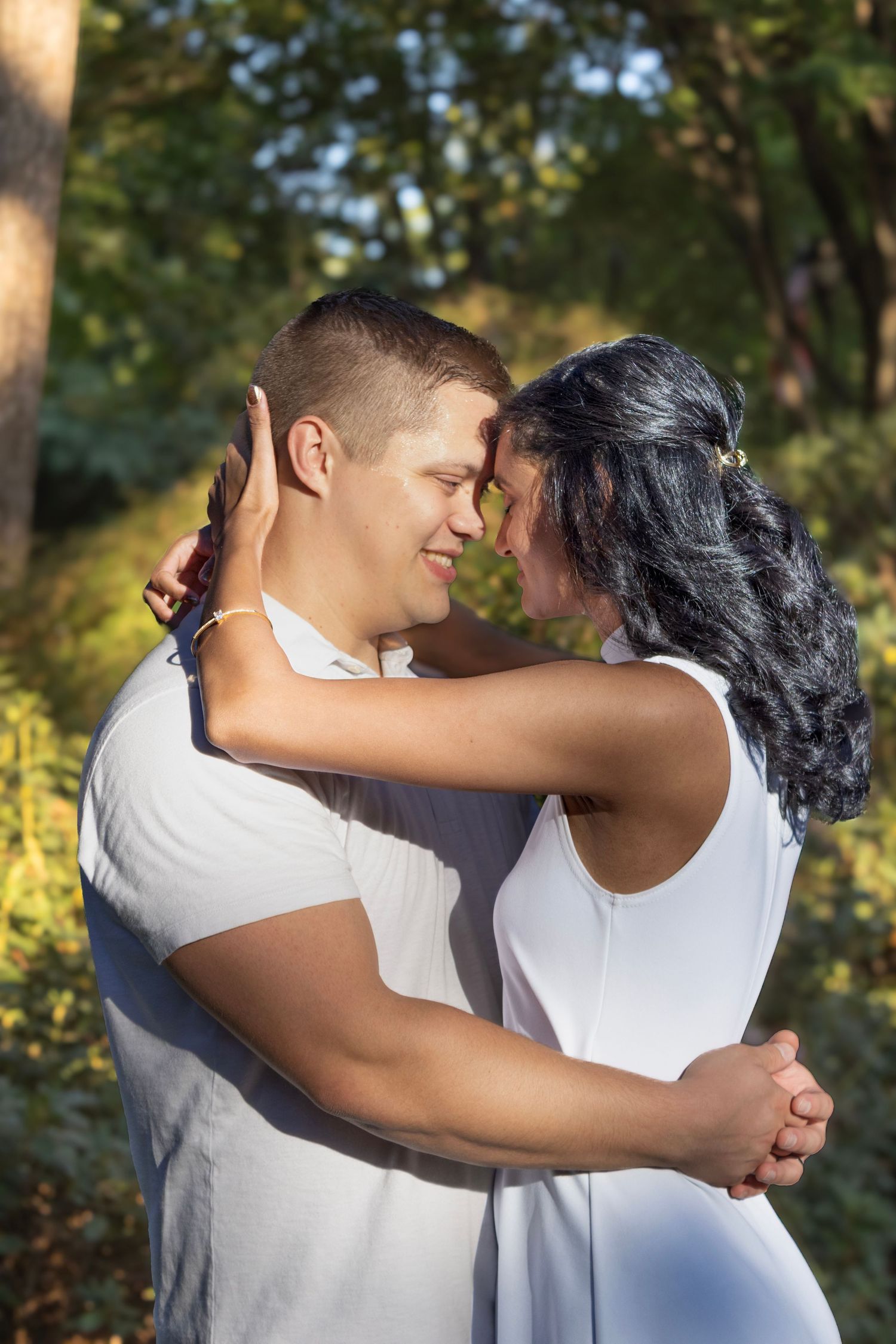 Couple in white shirts sharing romantic embraces in a sunlit outdoor setting.
