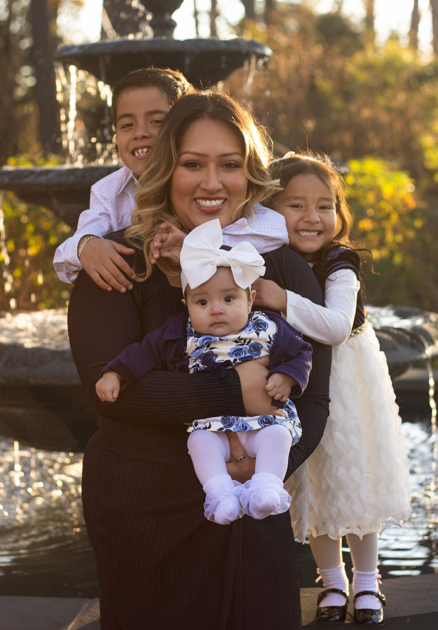 Family photo by water at sunset with children in formal white dresses.